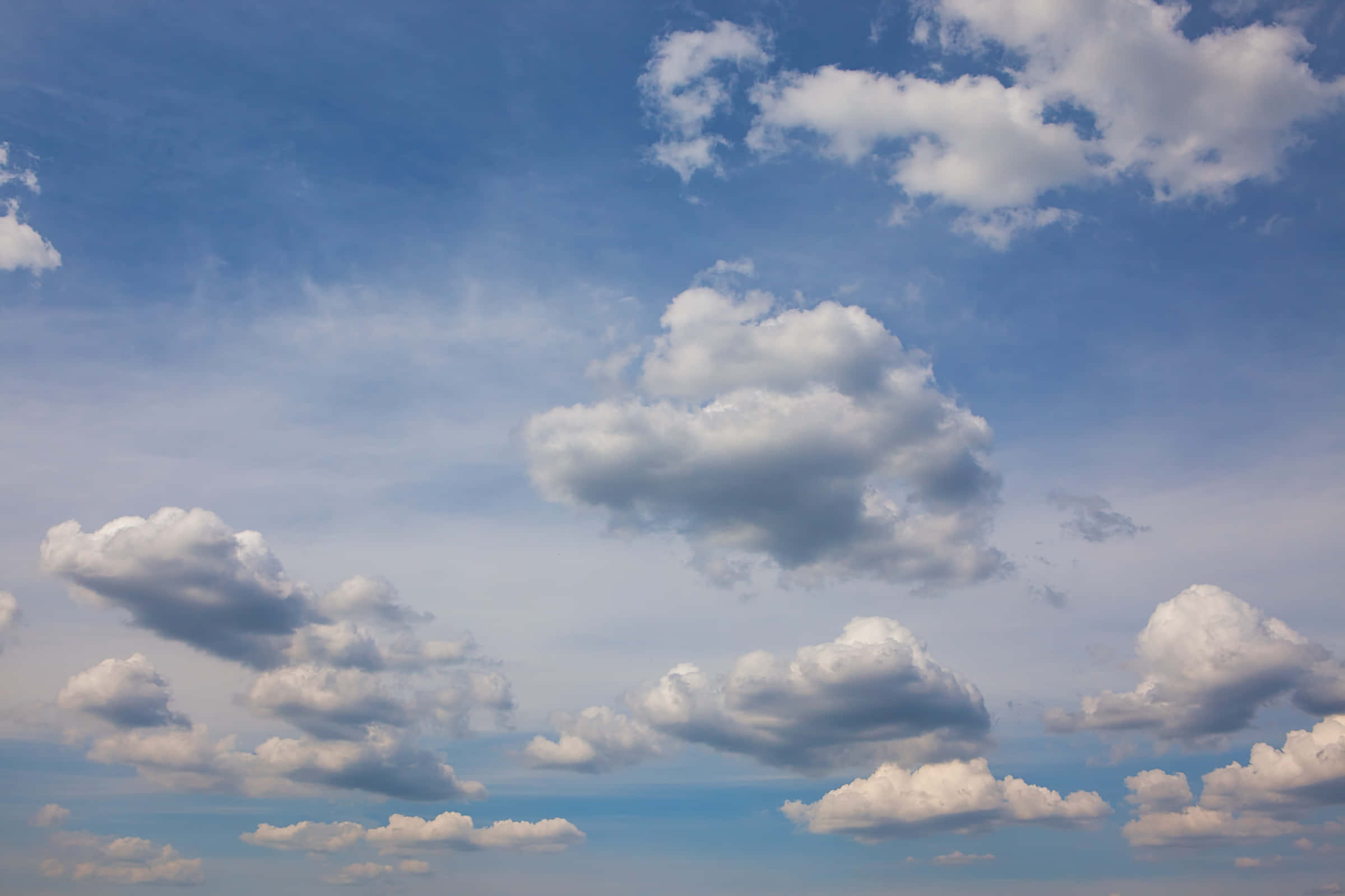 Blue Skies 桌布 壁紙 — 廣闊藍天，滿佈蓬鬆白雲，懶洋洋地飄過地平線。