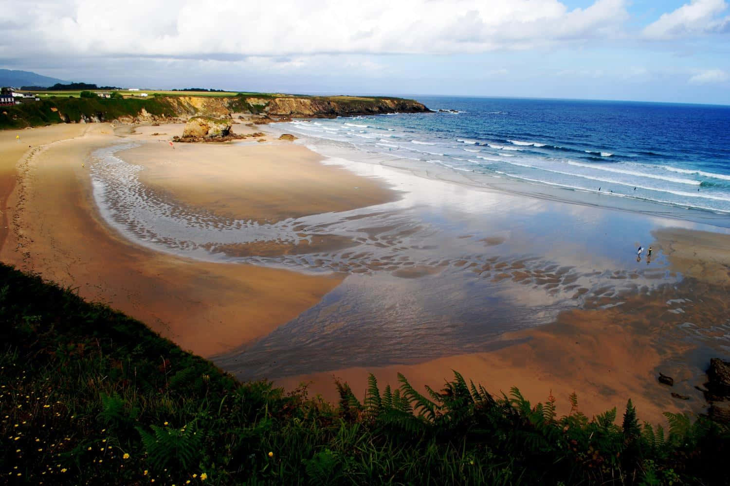 Spanish Beach 桌布 壁紙 — 廣闊視野，新月形沙灘上，在部分多雲的天空下，碧綠色的波浪翻滾而來。