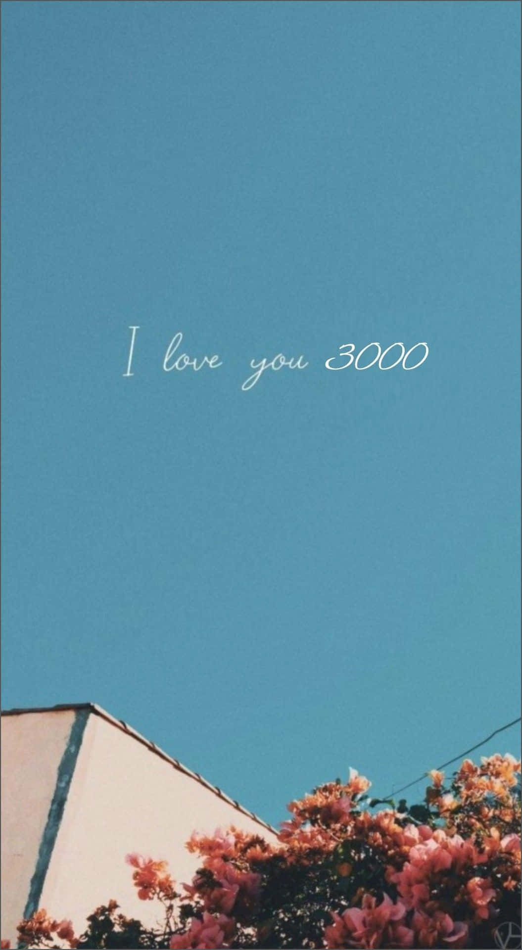桌布 壁紙 — 建築物和粉紅色開花灌木上方的晴朗藍天，手寫文字 I love you 3000。