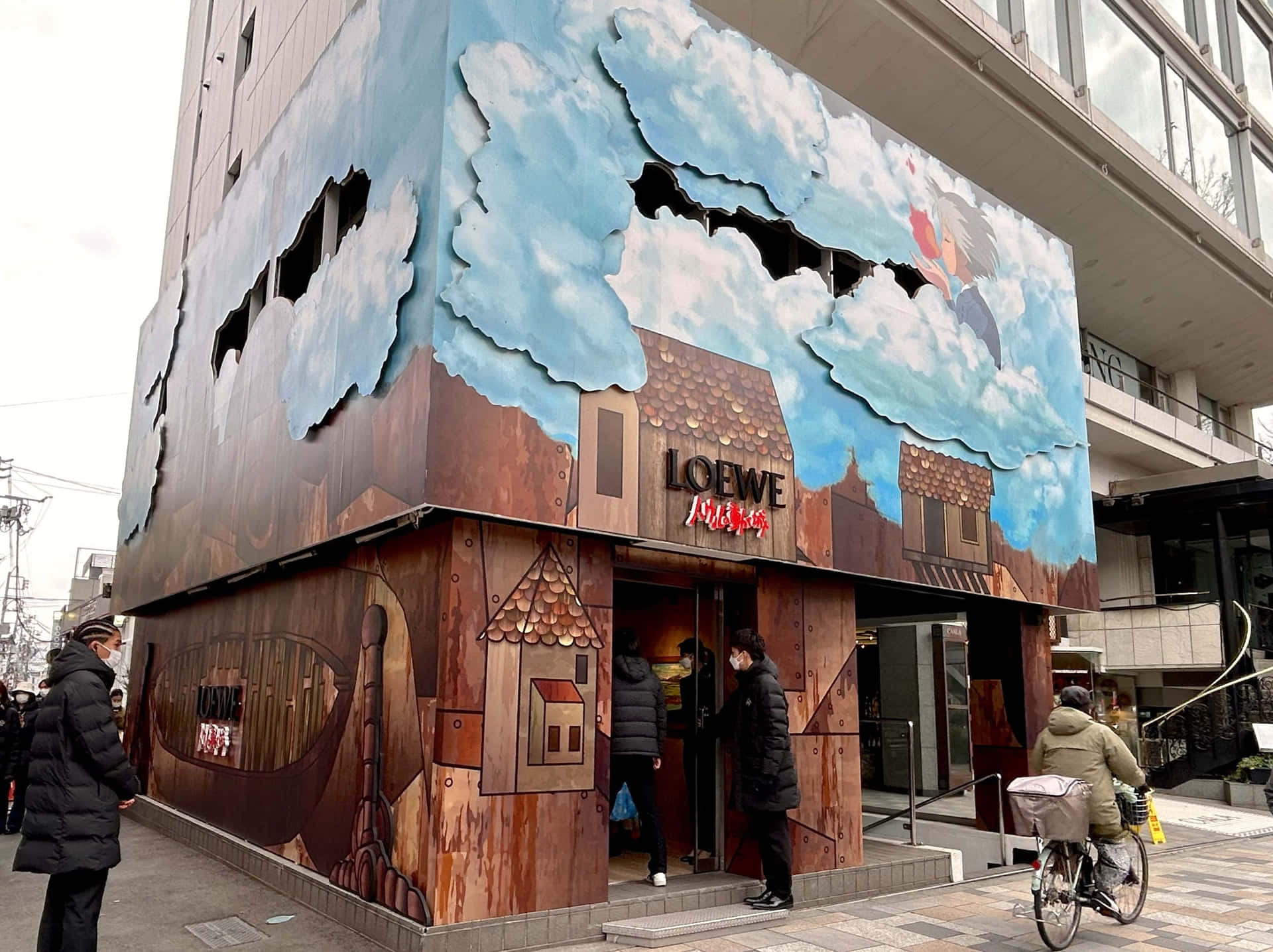 吉卜力工作室 桌布 壁紙 — 建築物外牆被繪製成看似質樸的木屋，有雲朵和一隻公雞衝破天空。
