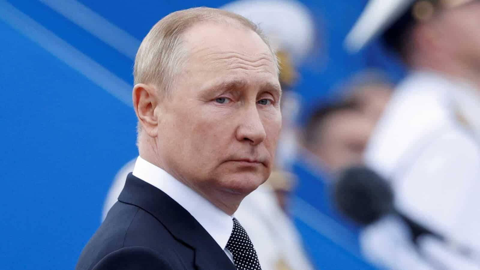 Leadership 桌布 壁紙 — 弗拉基米爾·普京身穿深色西裝打領帶的特寫肖像，背景為鮮豔的藍色，帶有模糊的人物。