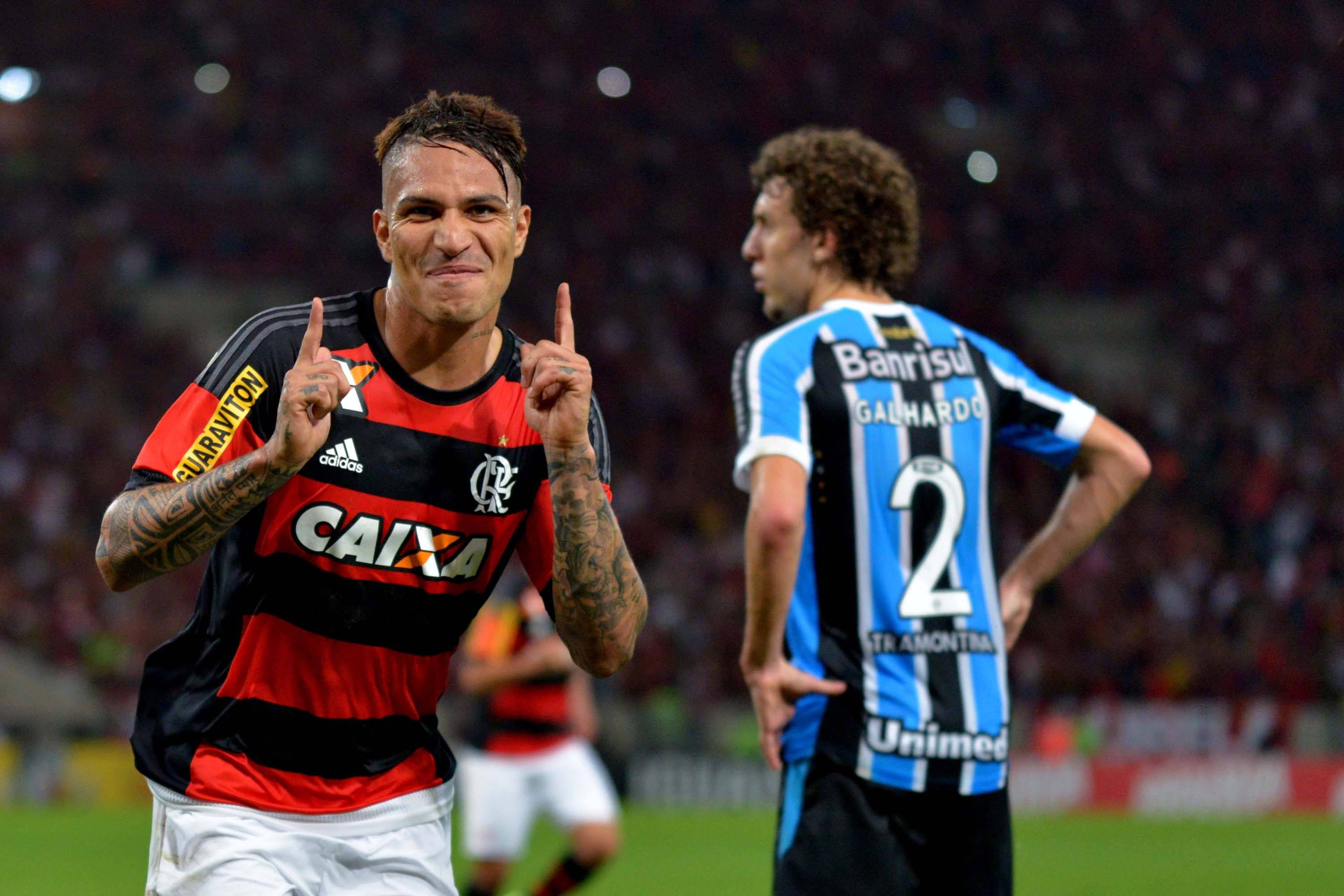 flamengo fc 桌布 壁紙 — 弗拉門戈足球員在夜間比賽中高舉雙食指慶祝，而對手球員則在失敗中觀望。