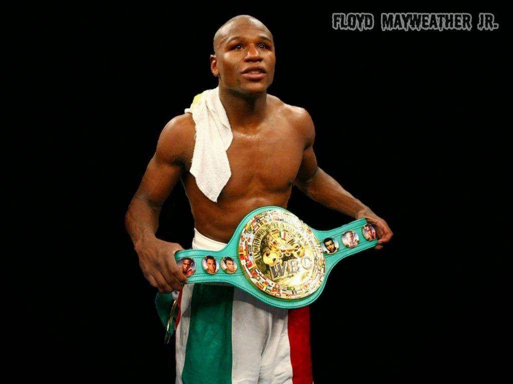 冠軍 桌布 壁紙 — 弗洛伊德·梅威瑟（Floyd Mayweather Jr.）自信地站在黑色背景前，肩上披著毛巾，手持WBC拳擊冠軍腰帶。