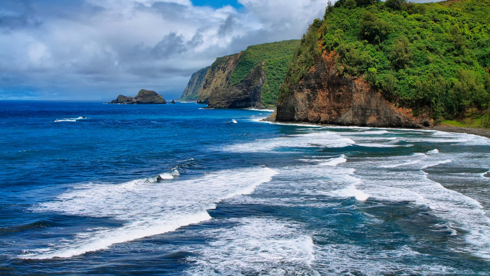Hawaiian Island 桌布 壁紙 — 強勁的海浪拍打著鬱鬱蔥蔥的綠色懸崖，天空烏雲密佈，場面壯觀。