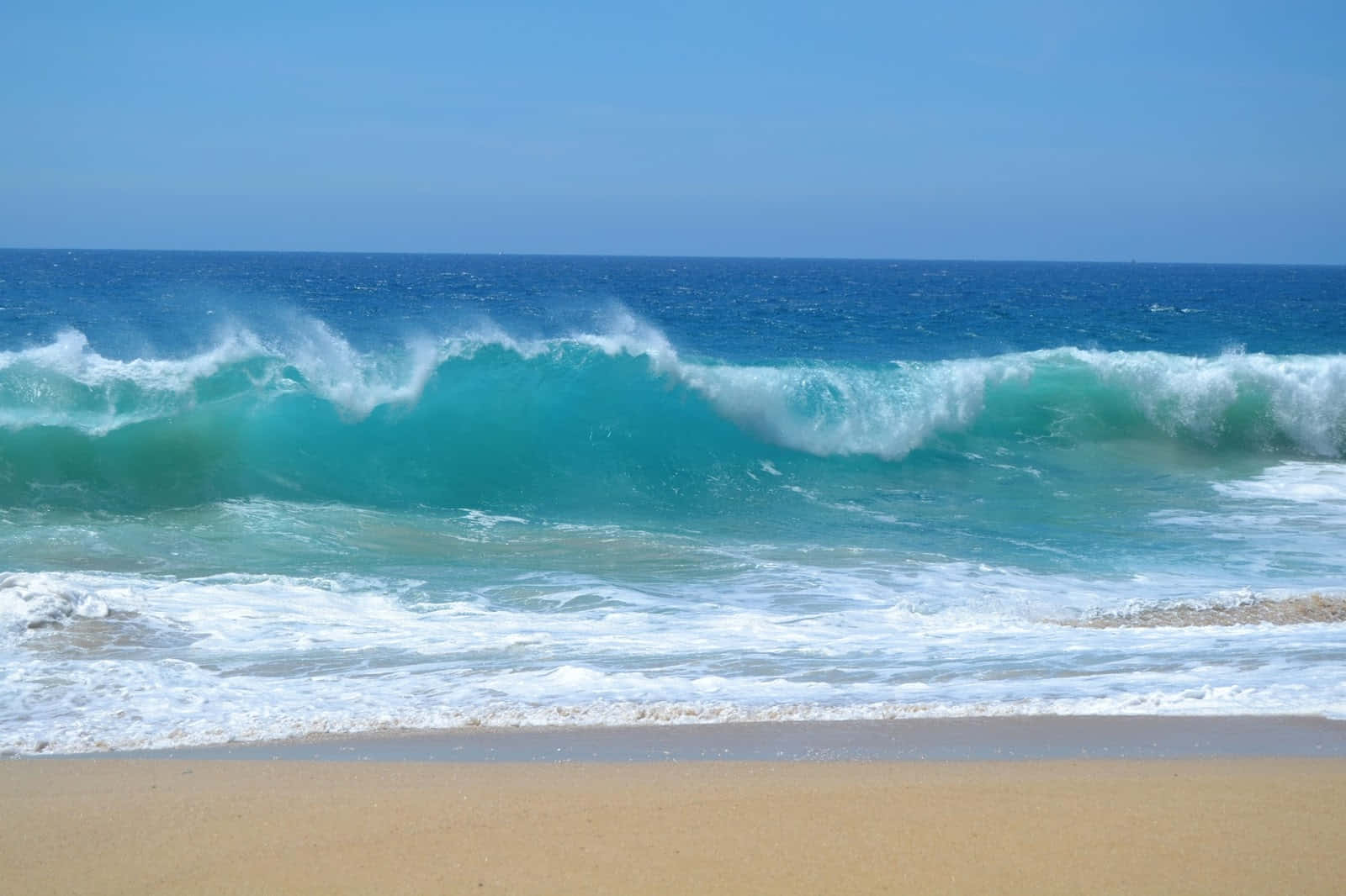 Beach Waves 桌布 壁紙 — 強勁的碧綠海浪拍打著金色沙灘，天空湛藍清澈。