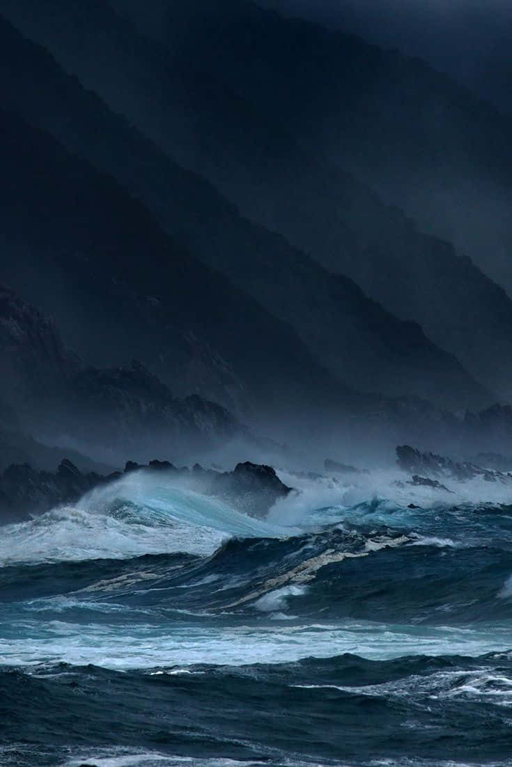 暴風 桌布 壁紙 — 強勁的藍綠色海浪在暴風雨陰暗的天空下衝擊著崎嶇的懸崖。