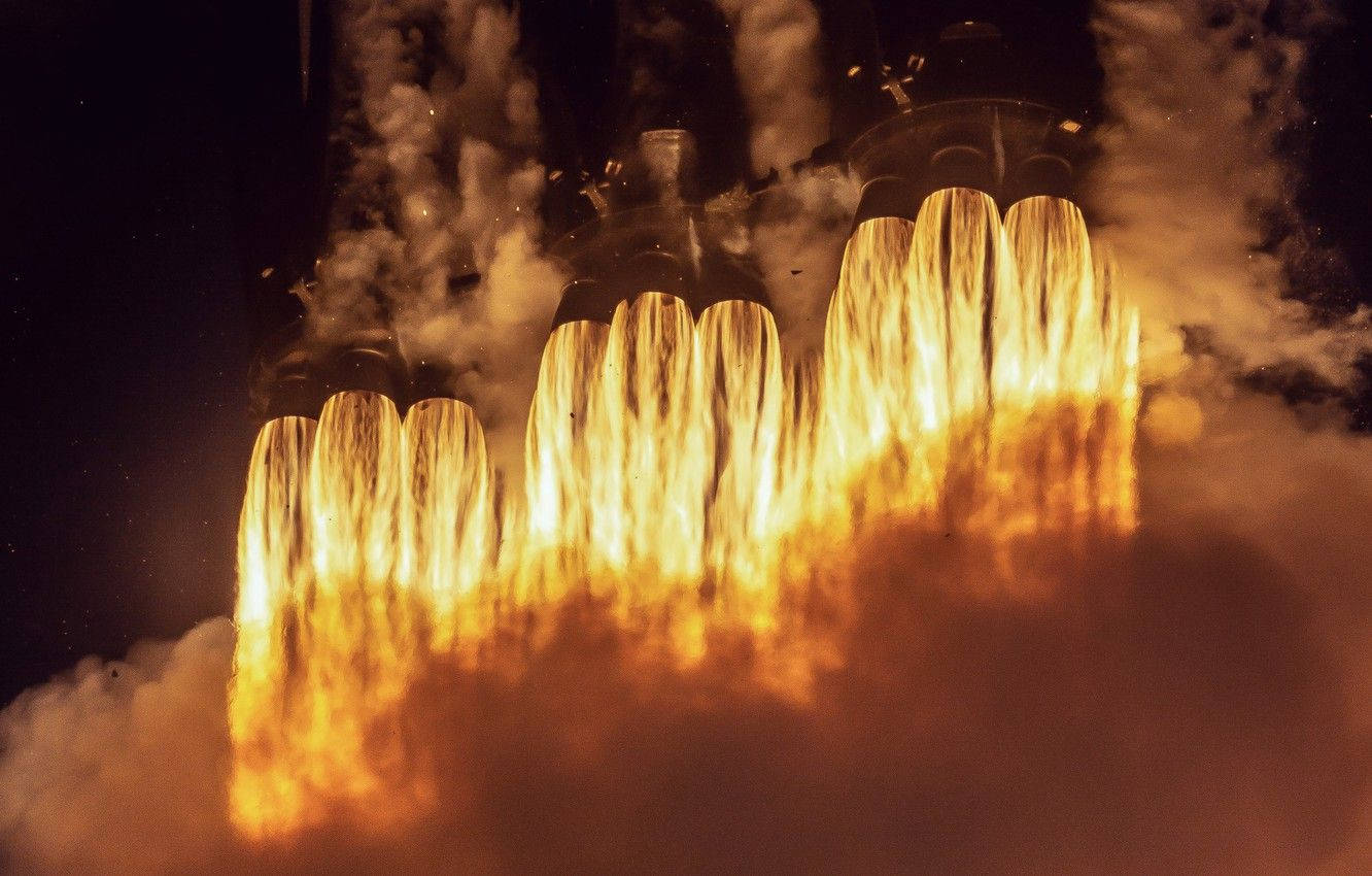 SpaceX 桌布 壁紙 — 強大的火箭引擎在黑暗的夜空中點燃，發出咆哮的橙色火焰和滾滾濃煙。