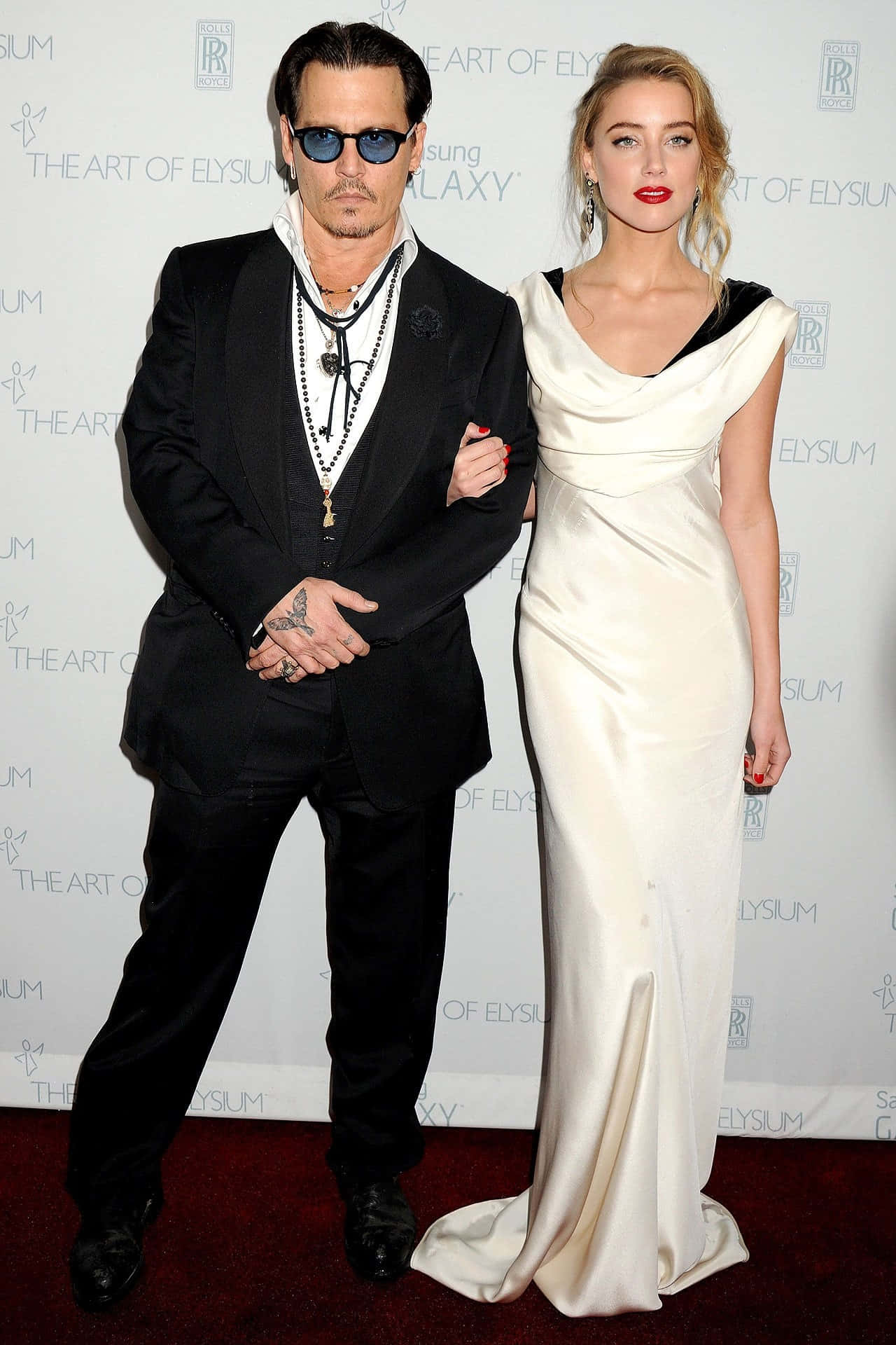 Johnny Depp And Amber Heard 桌布 壁紙 — 強尼戴普和安柏赫德在一個有品牌背景的正式活動中，優雅地在紅地毯上擺姿勢。
