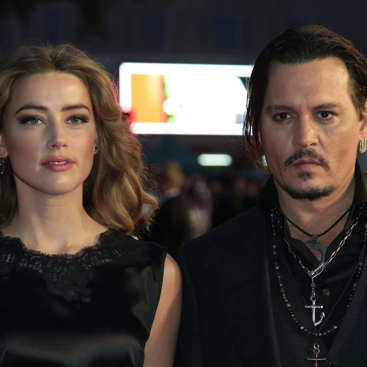Johnny Depp And Amber Heard 桌布 壁紙 — 強尼戴普和安柏赫德在明亮的燈光下並肩站在紅地毯活動上，背後是模糊的人群。
