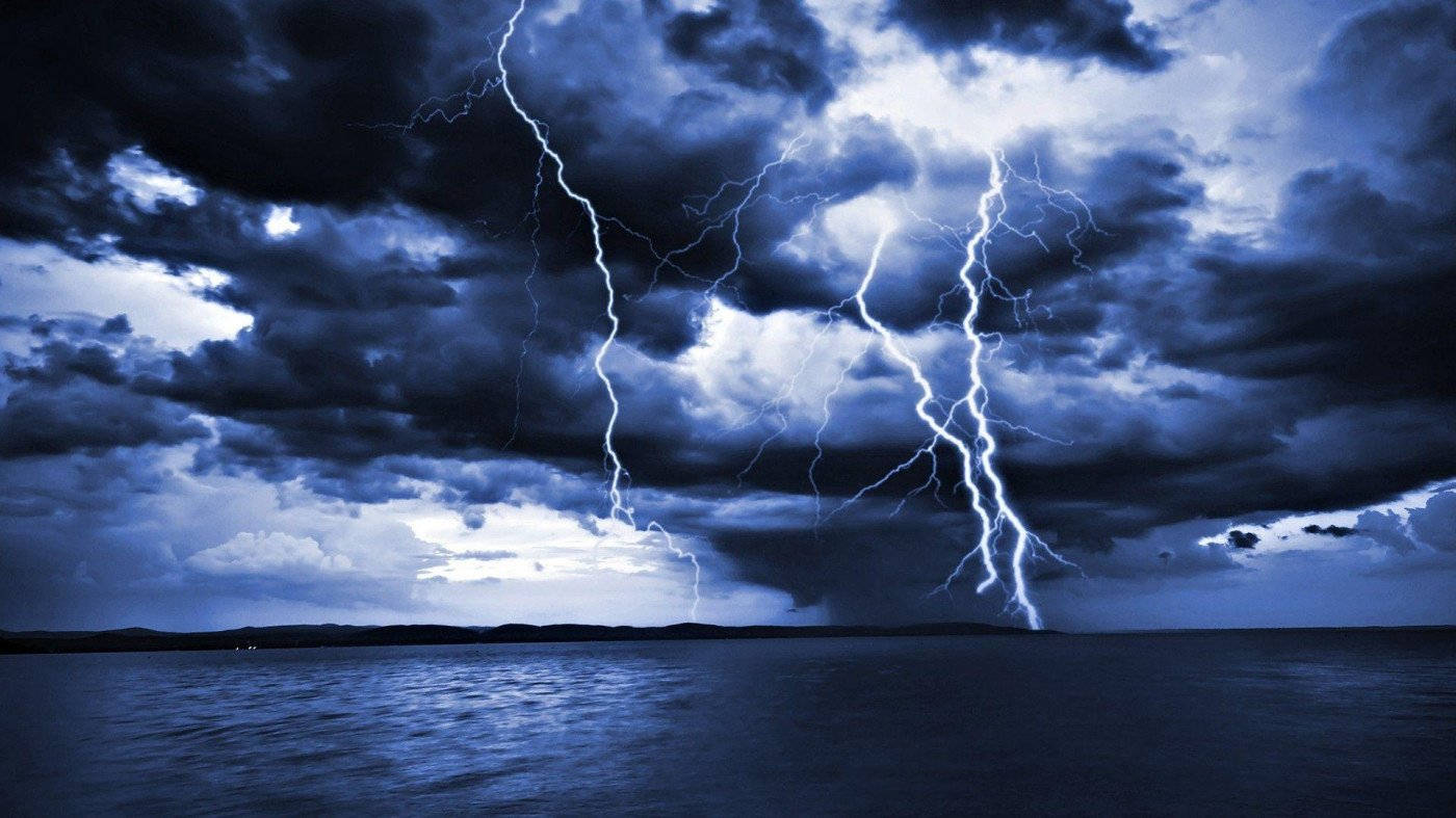閃電 桌布 壁紙 — 強烈的閃電在平靜的暗色水面上方的暴風雨藍色天空中劈啪作響。