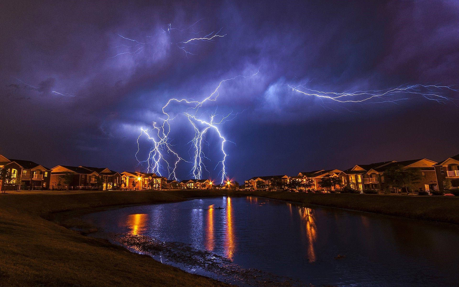 Oklahoma 桌布 壁紙 — 強烈的閃電照亮了郊區社區上空的暴風雨夜空，倒映在平靜的運河中。