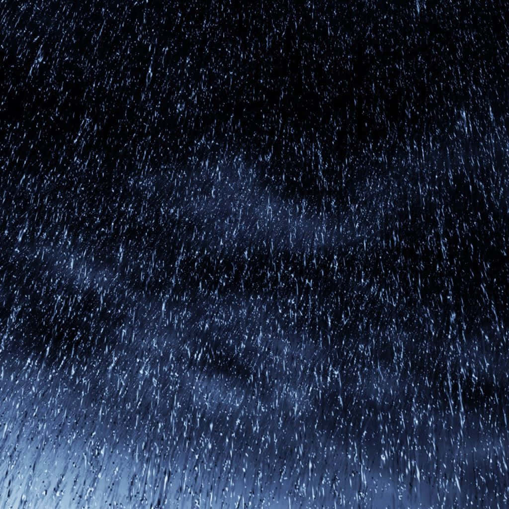 下雨 桌布 壁紙 — 強烈的雨絲從黑暗的夜空中落下，被下方冷藍色的光芒照亮。