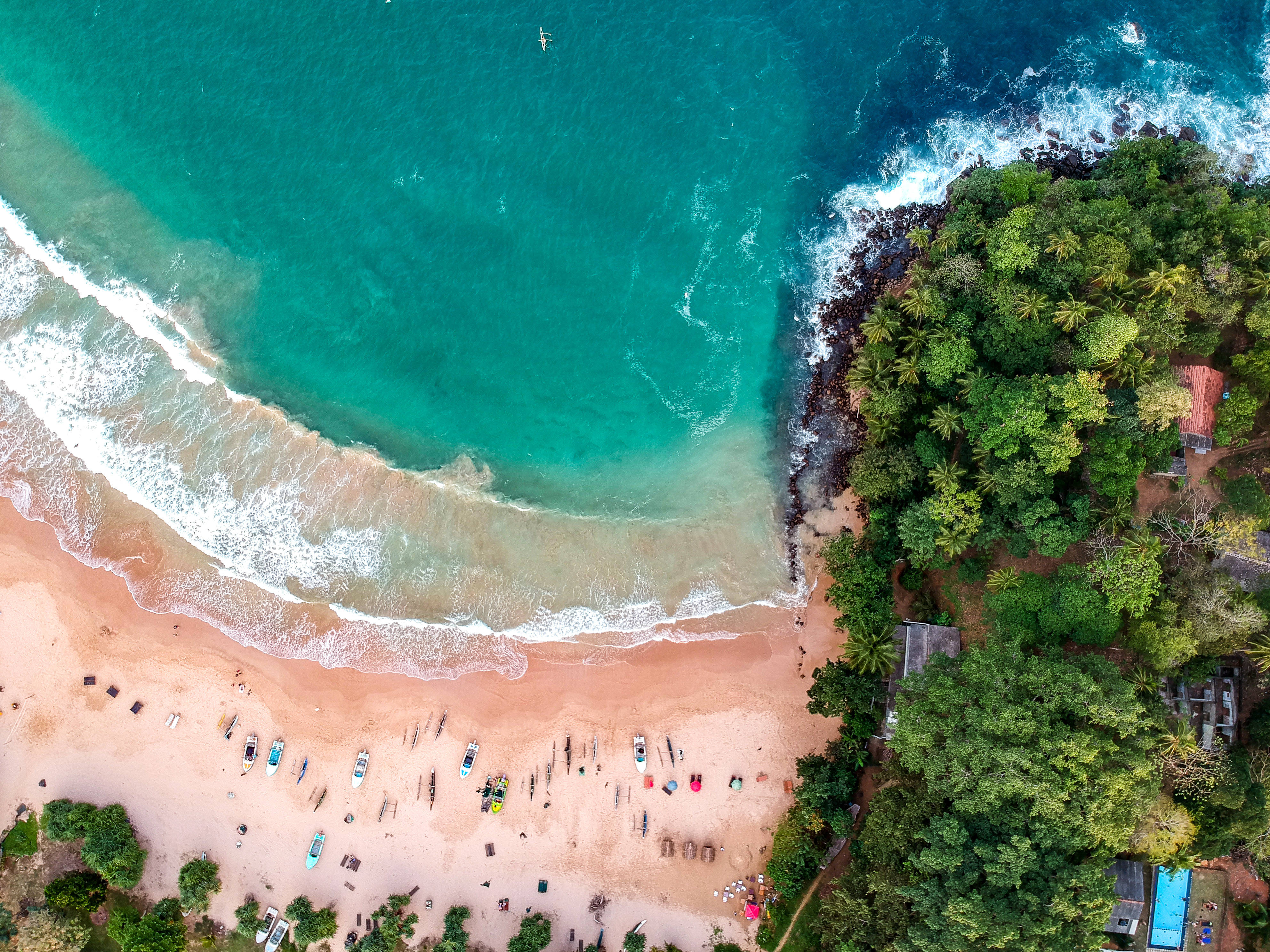 Sri Lanka 桌布 壁紙 — 彎曲的綠松石海灘的鳥瞰圖，白色海浪拍打著岩石海岸，兩旁是茂密的綠色叢林。