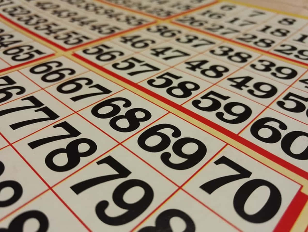 Bingo 桌布 壁紙 — 彩票網格的近距離特寫，奶油色背景上有粗體黑色數字，並以紅色和黃色邊框框住。