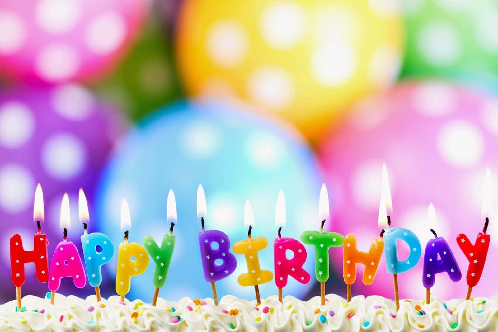 Birthday 桌布 壁紙 — 彩色字母蠟燭在灑有糖霜的蛋糕上拼出 happy birthday，背景是模糊的波點氣球。
