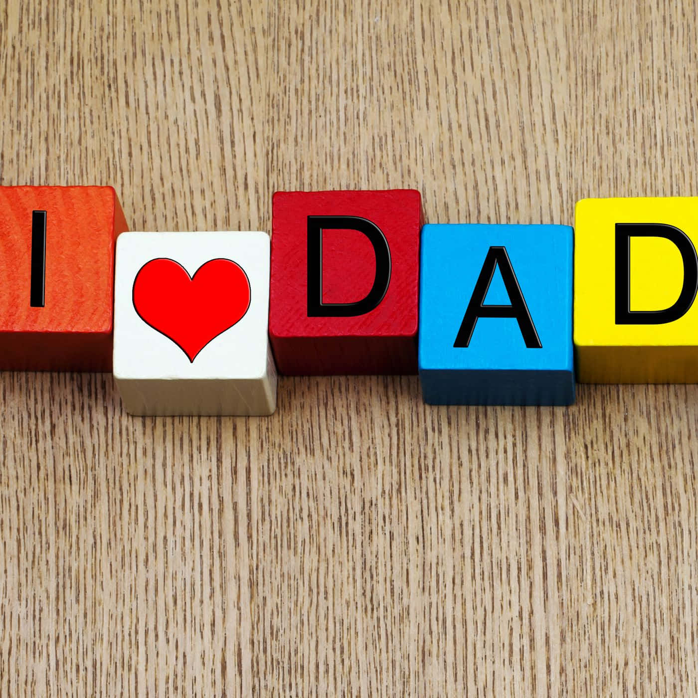 Fathers Day 桌布 壁紙 — 彩色木塊在淺色木面上用粗體字和紅色心形拼出「I ❤️ DAD」。
