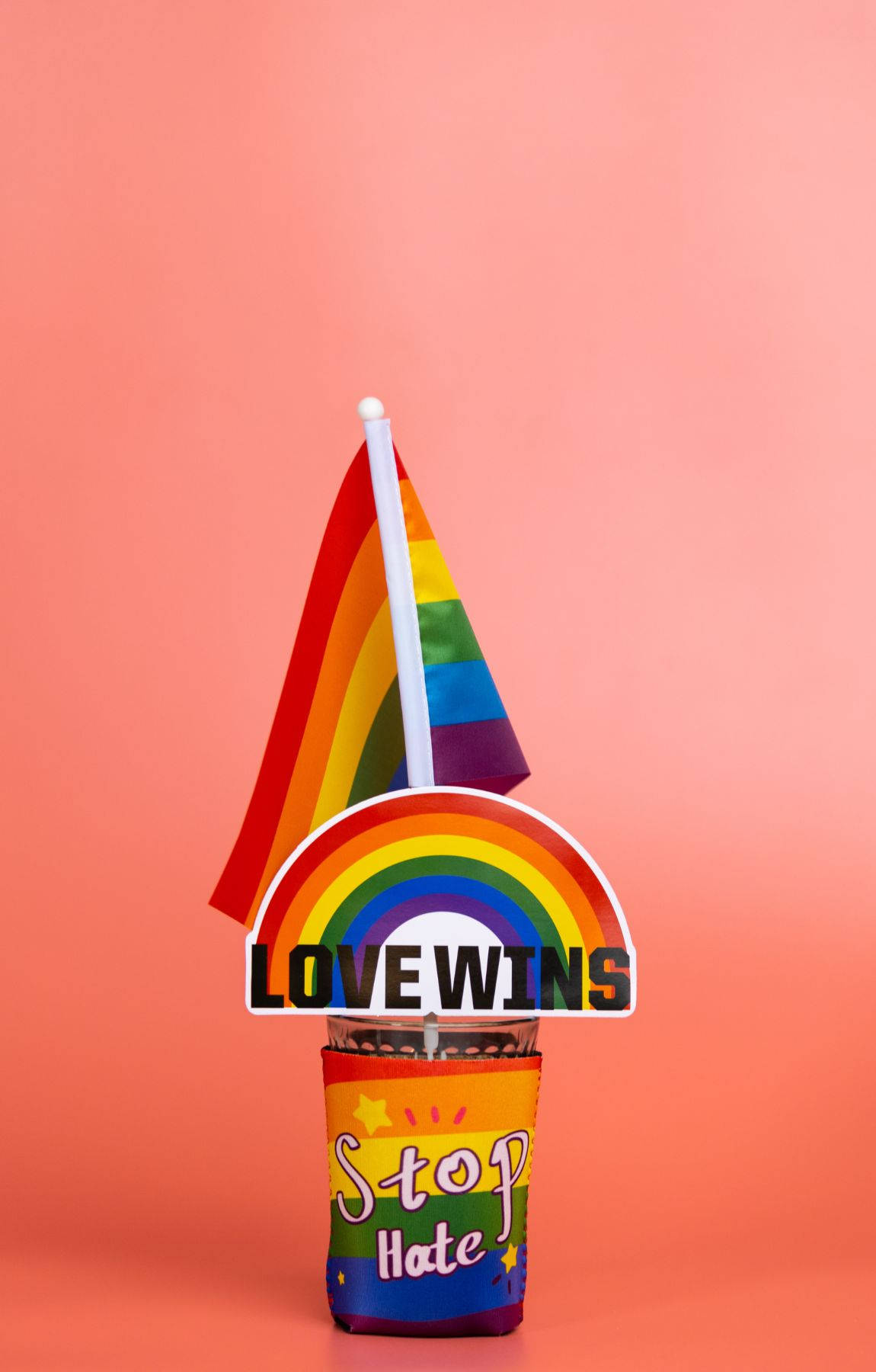 Subtle Lgbt 桌布 壁紙 — 彩虹旗和「LOVE WINS」標誌點綴著一個帶有「Stop Hate」文字的杯子，背景為柔和的粉紅色。