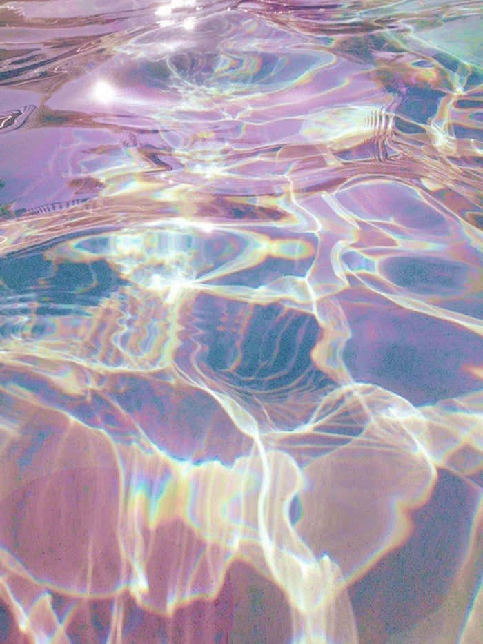 Hologram 桌布 壁紙 — 彩虹色的水波在明亮的陽光下閃爍著粉紫、粉紅和金色的柔和色調，營造出夢幻般的抽象圖案。