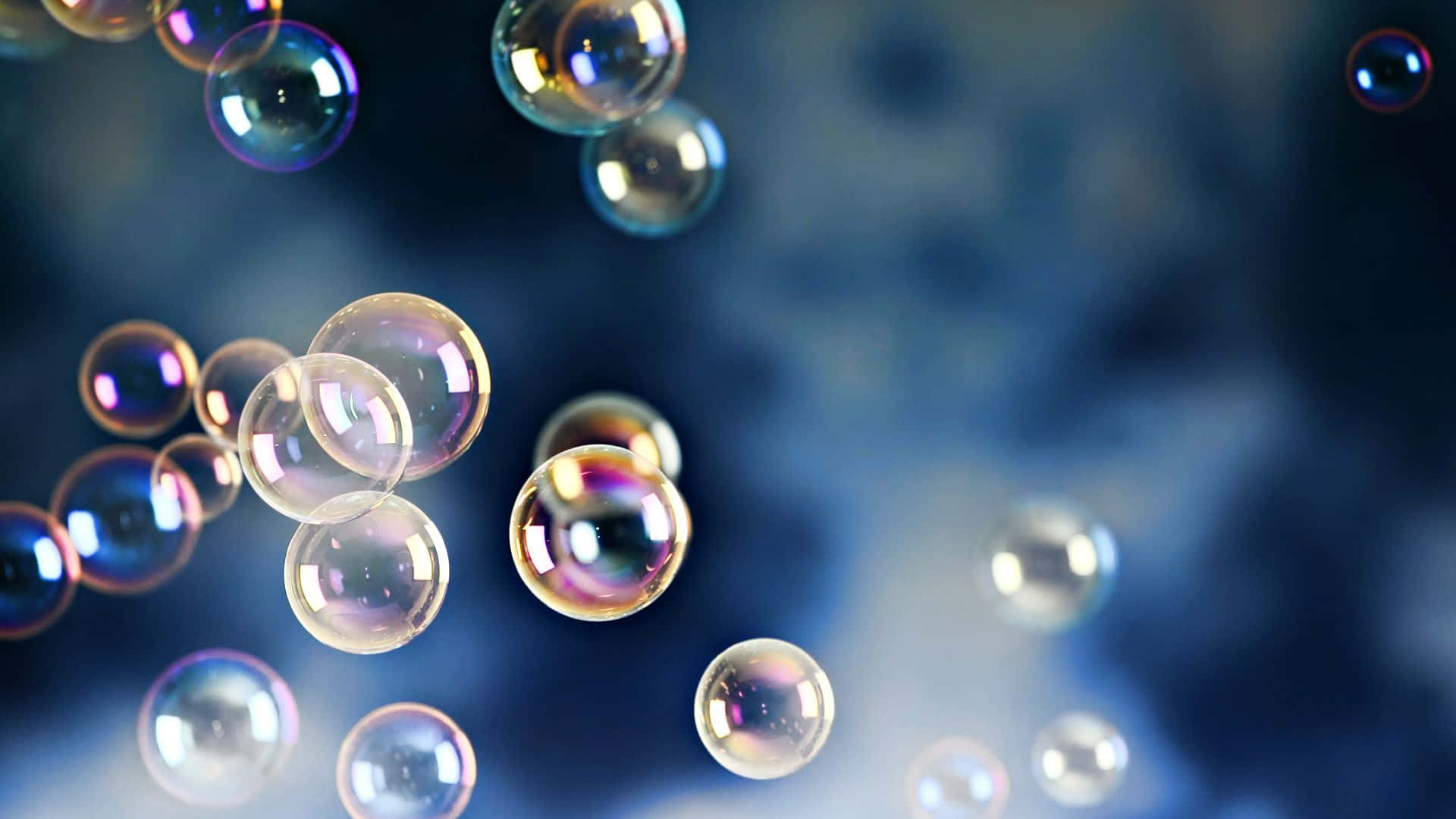 Bubbles 桌布 壁紙 — 彩虹色的肥皂泡在柔和的模糊藍色背景上漂浮並閃爍。