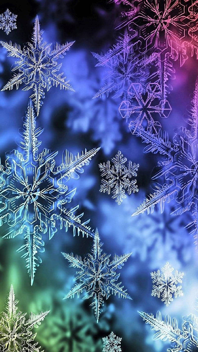 發光的雪花漂浮在色彩繽紛的漸變天空中，帶有藍色、紫色和綠色色調。 — 雪花 GIF 壁紙