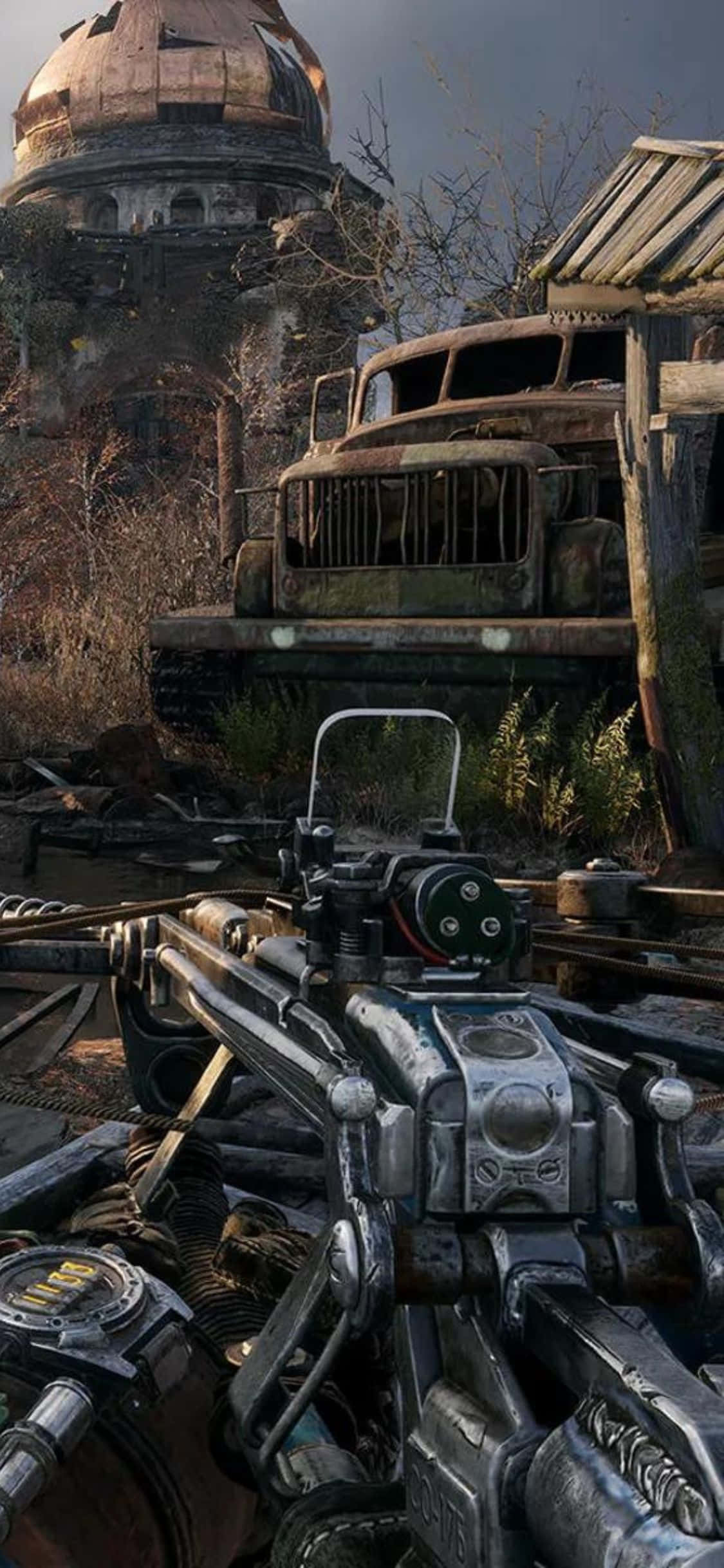 iPhone X Metro Exodus 桌布 壁紙 — 後末日荒原中，一把未來武器瞄準一輛生鏽卡車旁邊正在崩塌的圓頂建築的第一人稱視角。