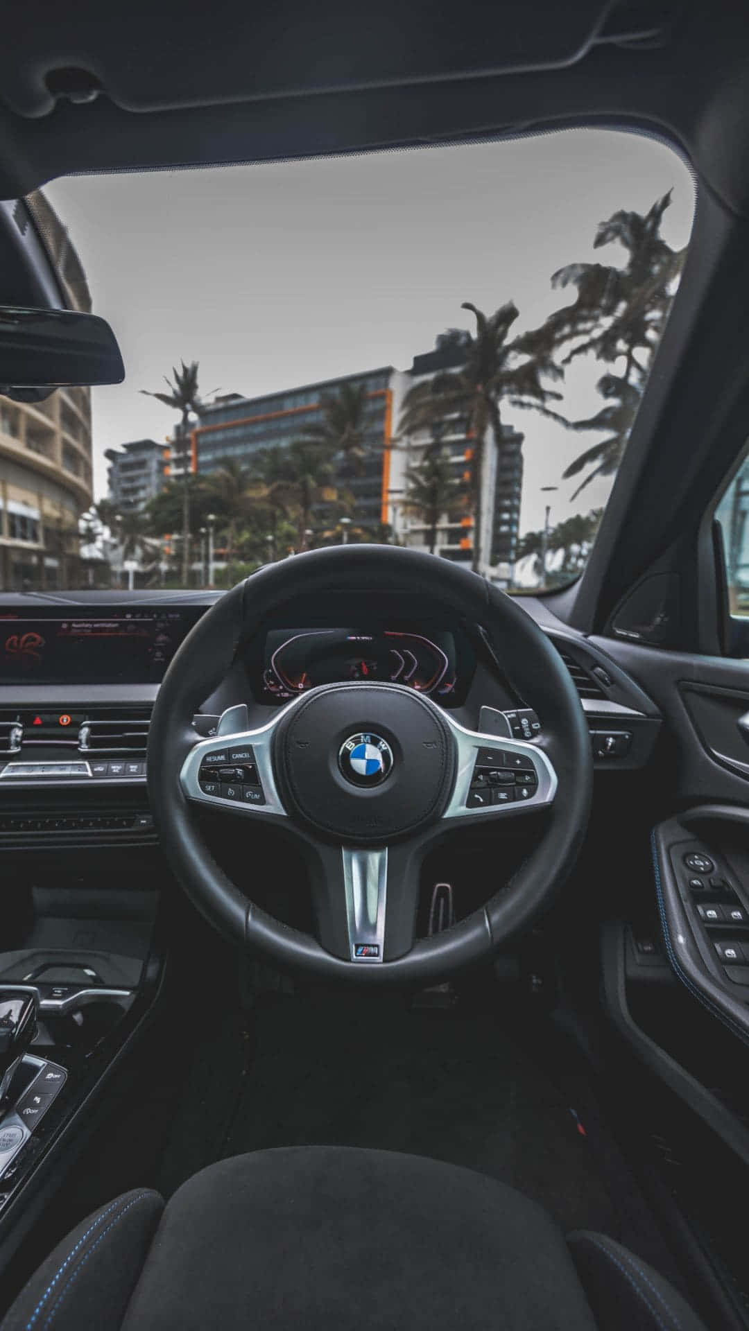 Inside Car 桌布 壁紙 — 從BMW汽車駕駛座看到的內部景觀，透過擋風玻璃可以看到棕櫚樹和城市建築。