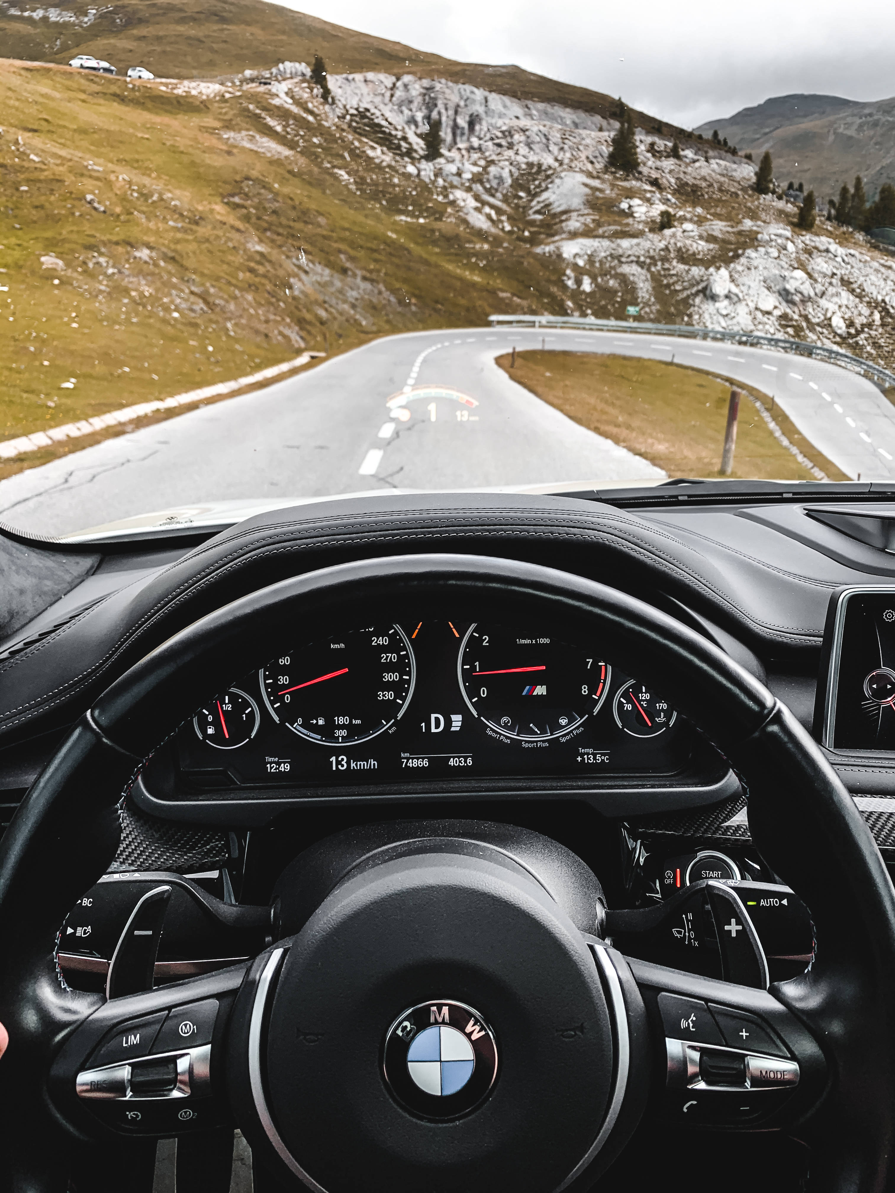 cars 桌布 壁紙 — 從BMW車內看到的駕駛者視角，行駛在蜿蜒的山路上，兩旁是被雪覆蓋的小山丘，天空多雲。