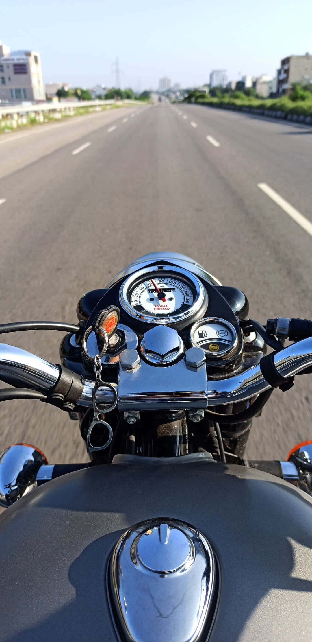 Royal Enfield Bullet 桌布 壁紙 — 從一輛鍍鉻機車在晴朗藍天下沿寬闊城市高速公路疾駛的第一人稱視角。