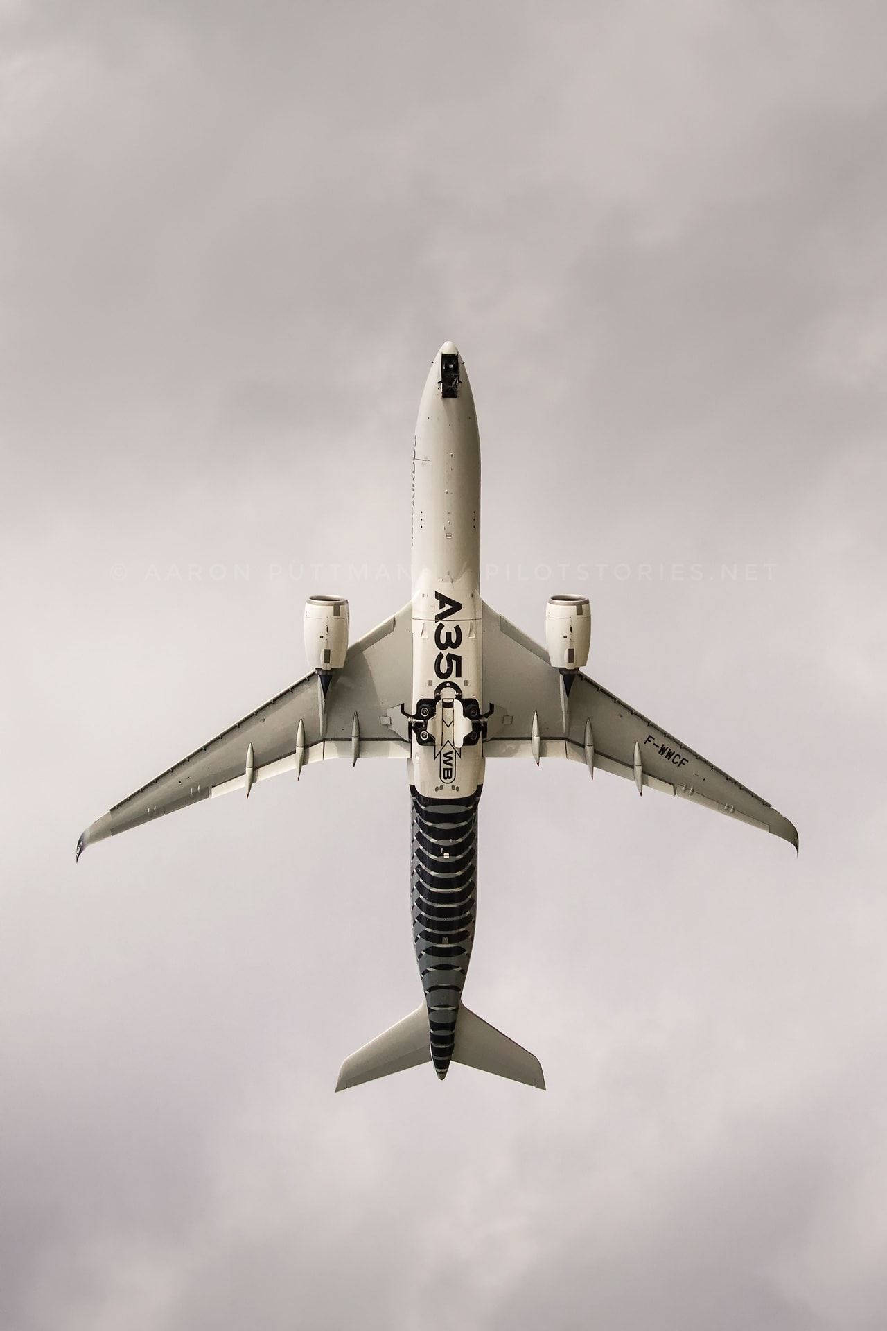 飛機 桌布 壁紙 — 從上往下看一架空中巴士A350在陰天灰色天空下飛過頭頂。