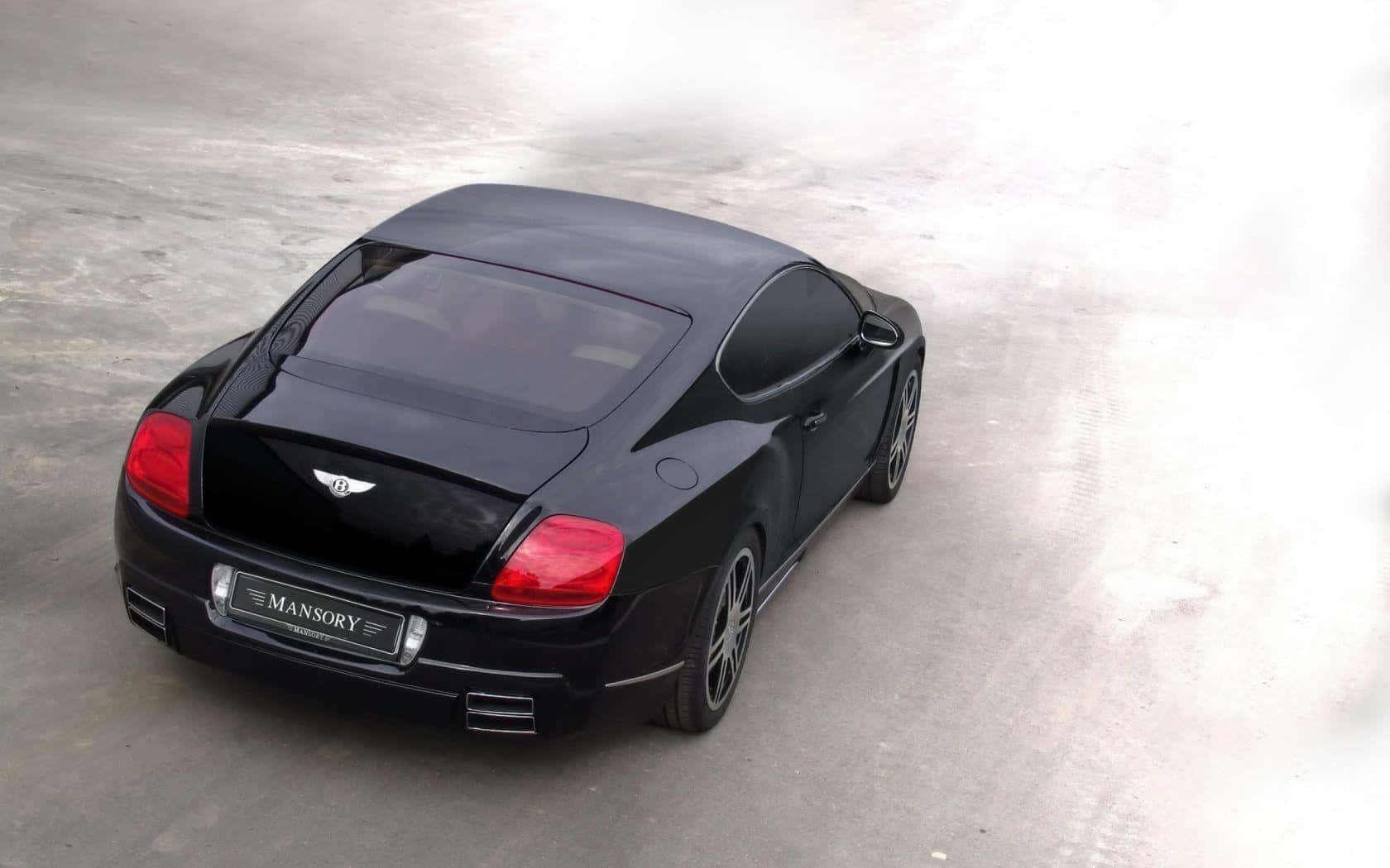 豪華車 桌布 壁紙 — 從上方俯瞰，一輛光滑的黑色 Mansory 改裝 Bentley Continental GT 雙門轎跑車停在混凝土表面上。