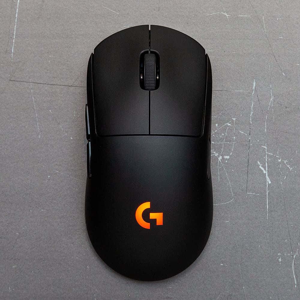Gaming Accessories 桌布 壁紙 — 從上方俯瞰，一隻黑色Logitech遊戲滑鼠在刮花的灰色表面上，帶有發光的橙色標誌。