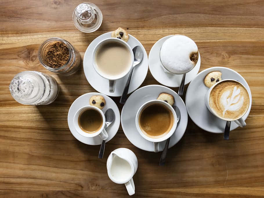 Milk And Coffee 桌布 壁紙 — 從上方俯瞰，各種咖啡飲品和餅乾整齊擺放在溫暖的木桌上。