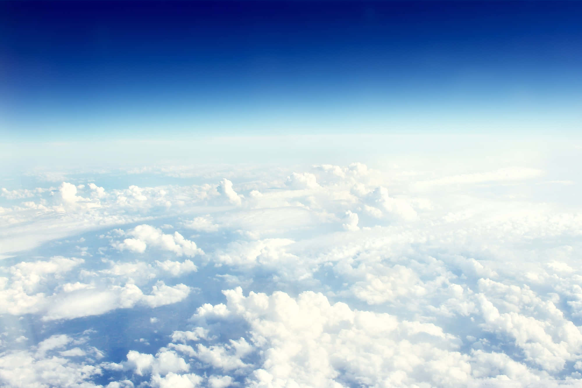 Clouds Aesthetics 桌布 壁紙 — 從上方俯瞰，在深藍色天空下延伸的蓬鬆白雲的鳥瞰圖。