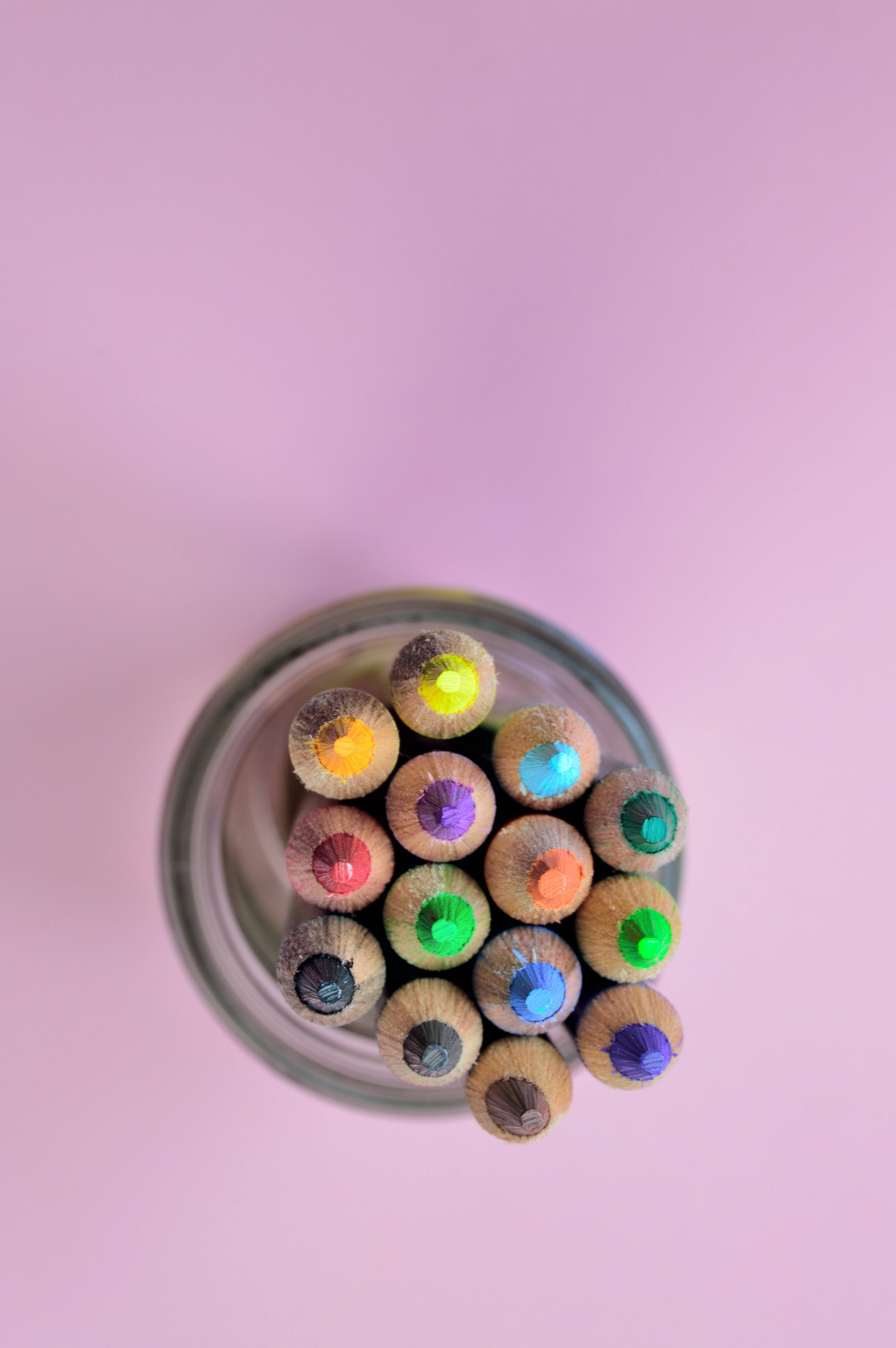 pencil 桌布 壁紙 — 從上方俯瞰，彩色鉛筆尖從玻璃罐中探出頭來，背景是柔和的粉紅色。