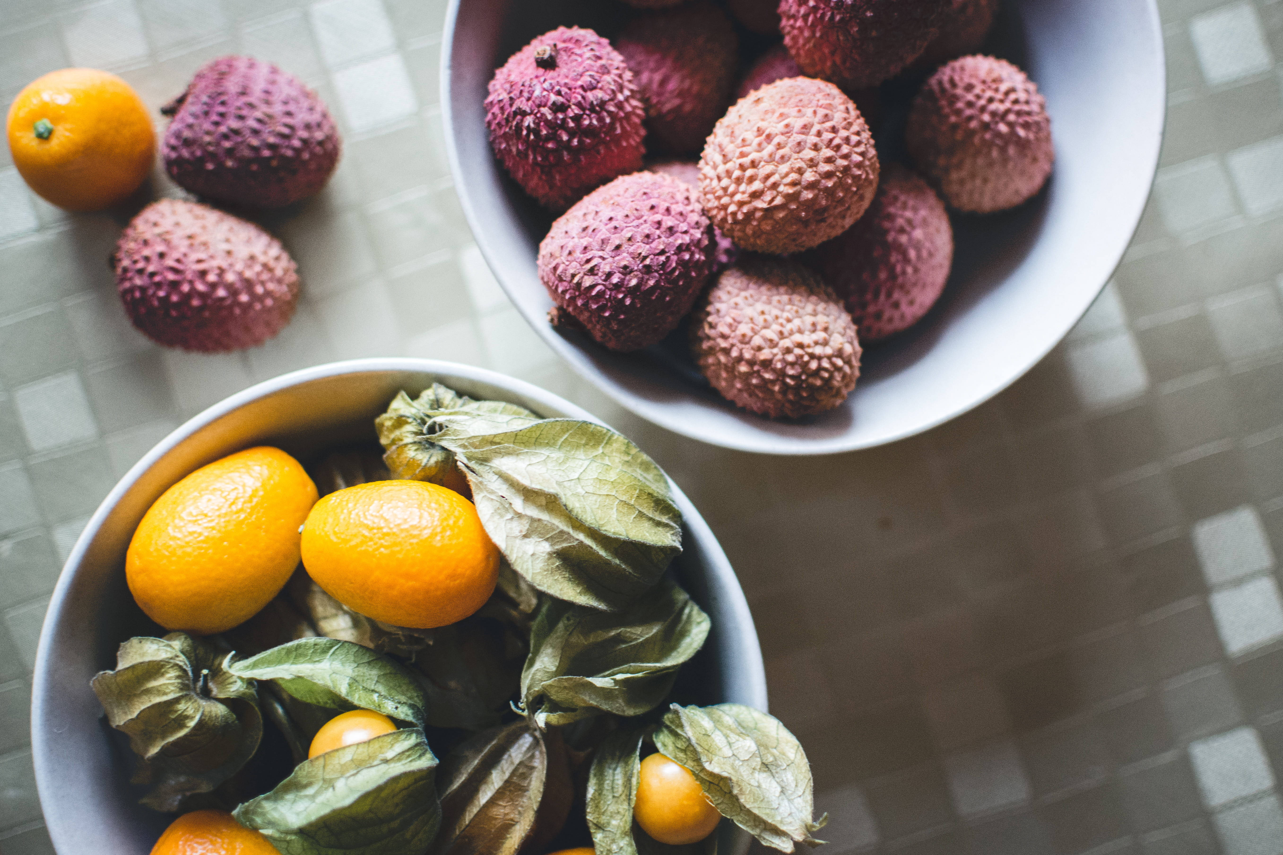 citrus 桌布 壁紙 — 從上方俯瞰，格子桌布上放著盛滿鮮豔荔枝和金黃金橘的碗。