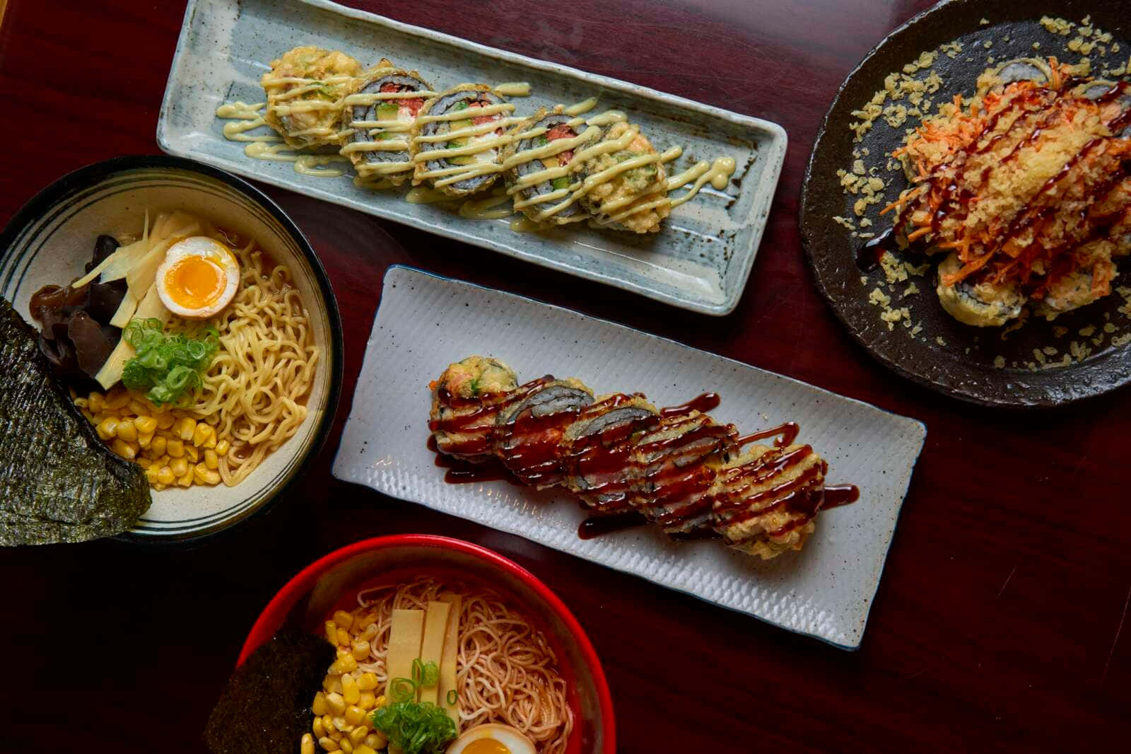 Noodles 桌布 壁紙 — 從上方俯瞰，深色木桌上擺放著各式日本料理，包括拉麵碗和天婦羅卷。