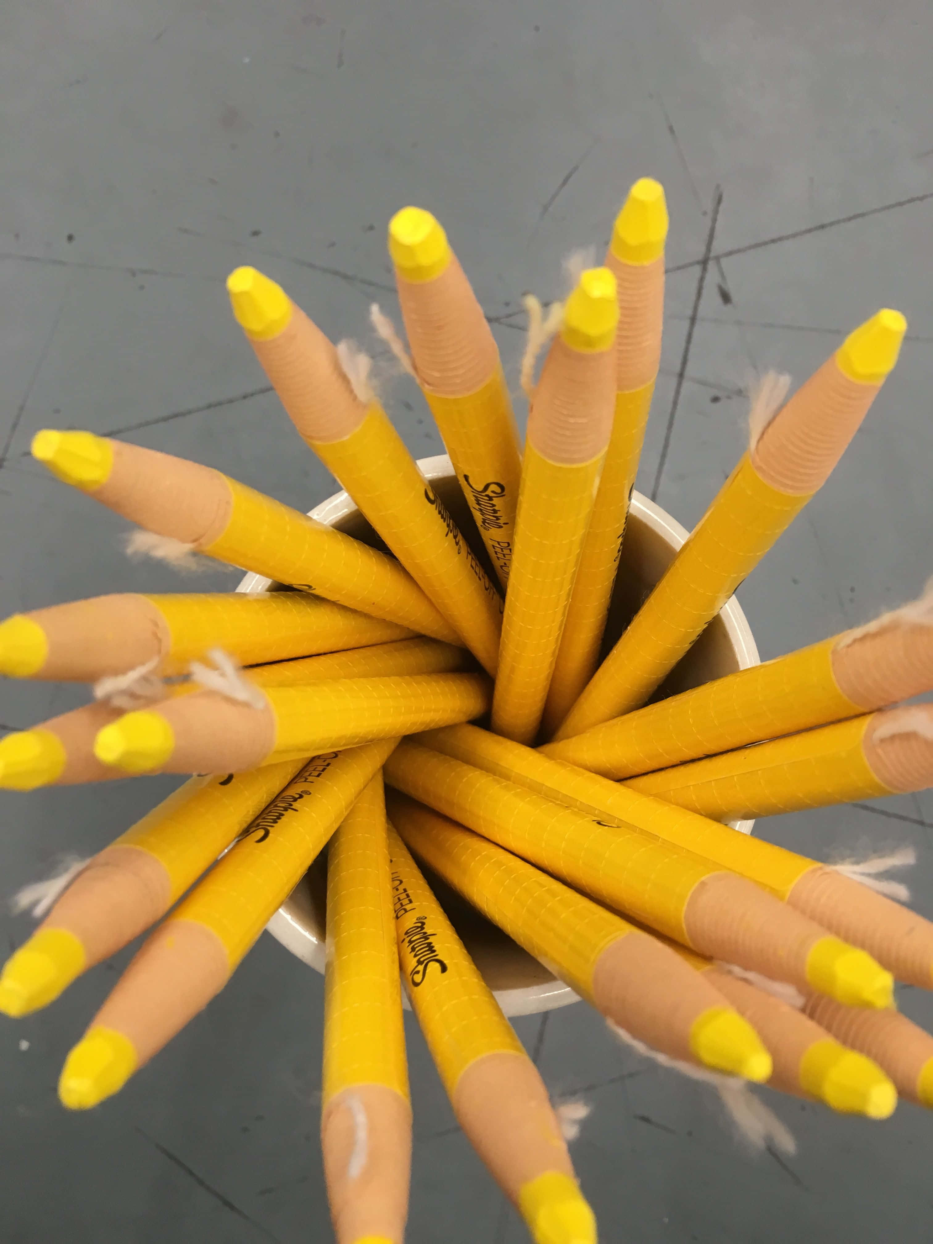 可愛 桌布 壁紙 — 從上方俯瞰，灰色地板上的白色杯子中散發出黃色鉛筆，筆尖磨損。
