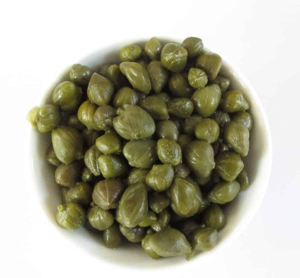 plants 桌布 壁紙 — 從上方俯瞰，白色陶瓷碗中裝滿了光澤的綠色酸豆，背景是純白色。