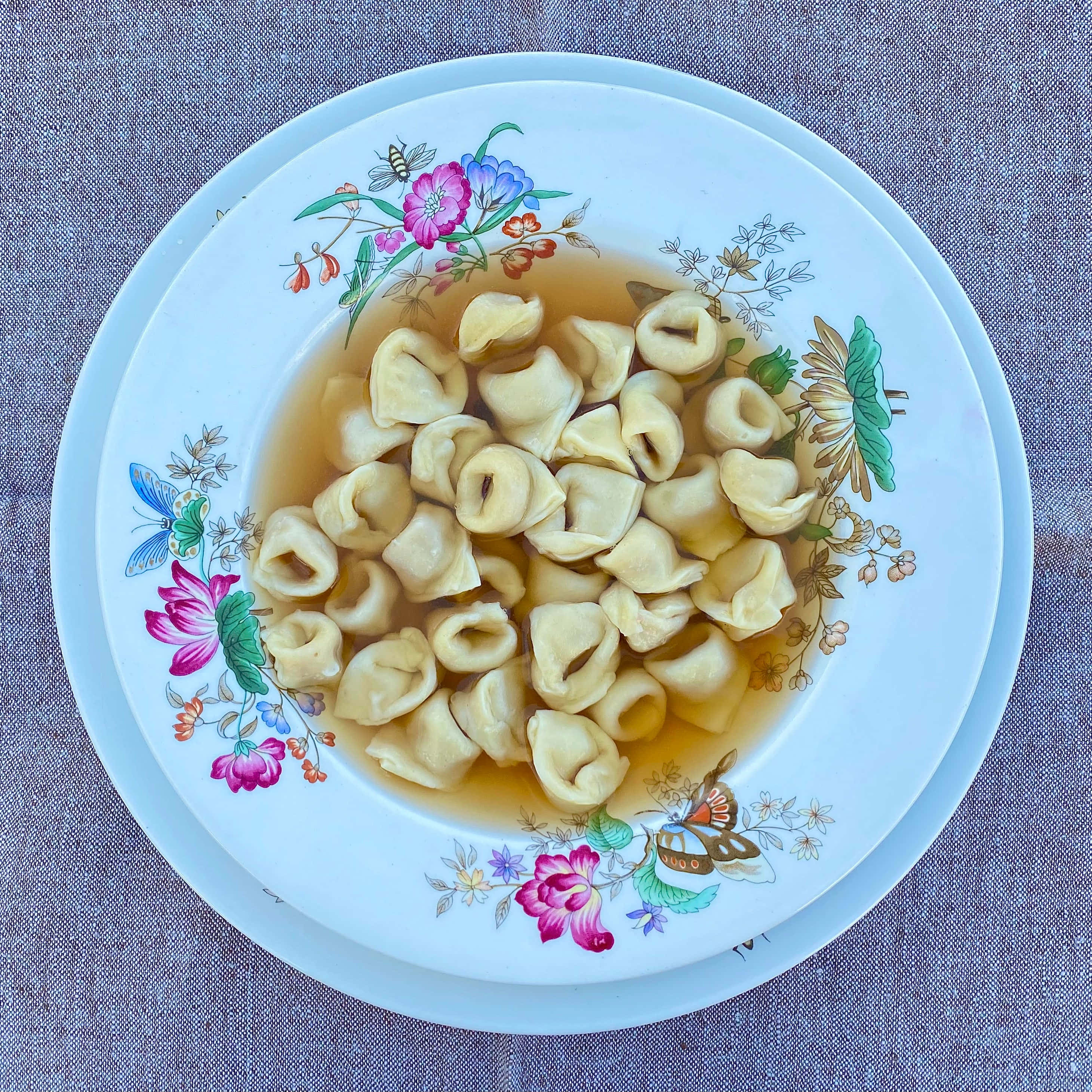Food Photography 桌布 壁紙 — 從上方俯瞰，花紋盤上盛載著清湯義大利雲吞，盤子置於有紋理的灰色表面上。