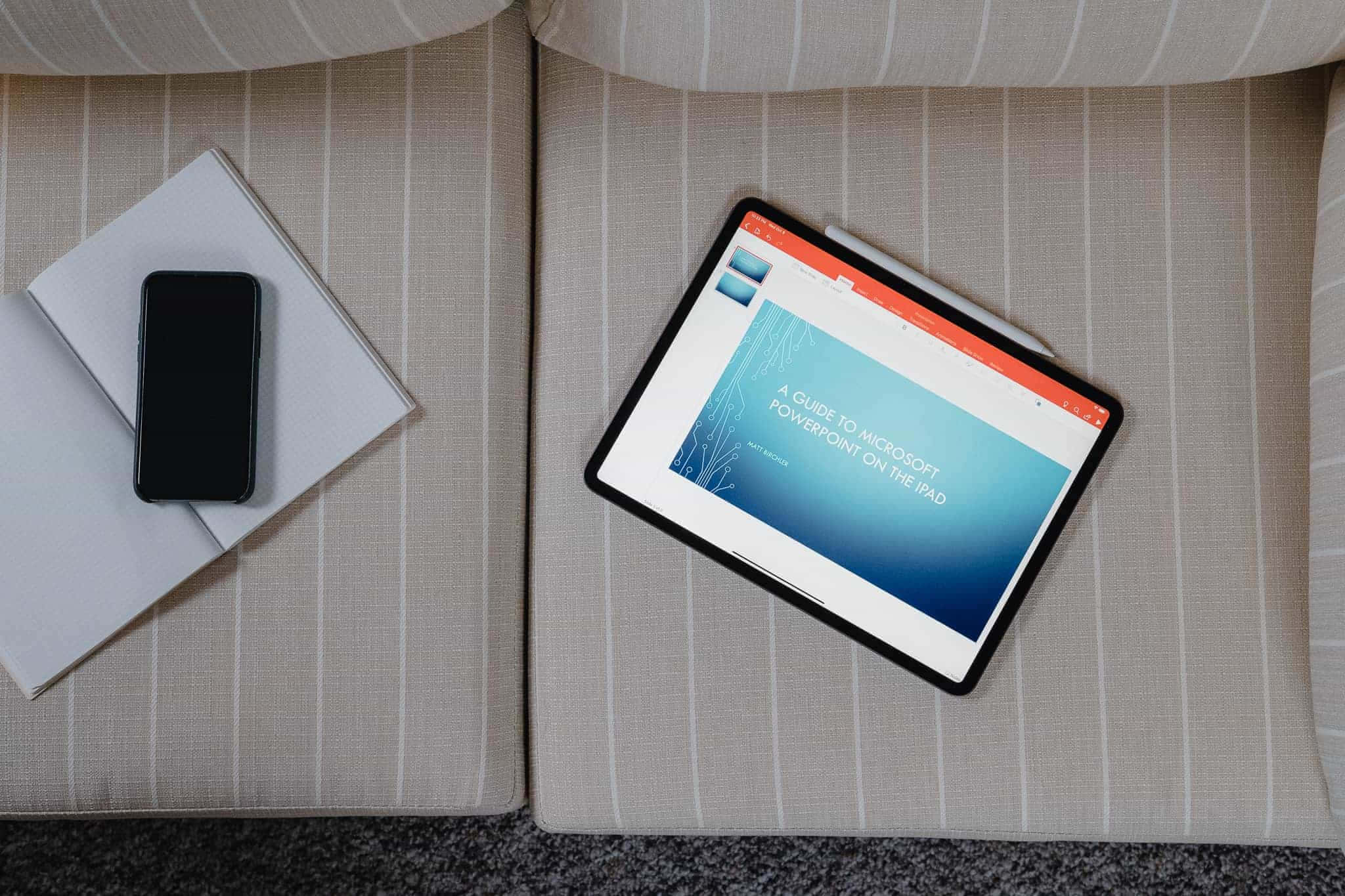 Powerpoint 桌布 壁紙 — 從上方俯瞰一個平板電腦顯示 PowerPoint 指南在 iPad 上，放在條紋沙發上，旁邊有智慧型手機和筆記本。