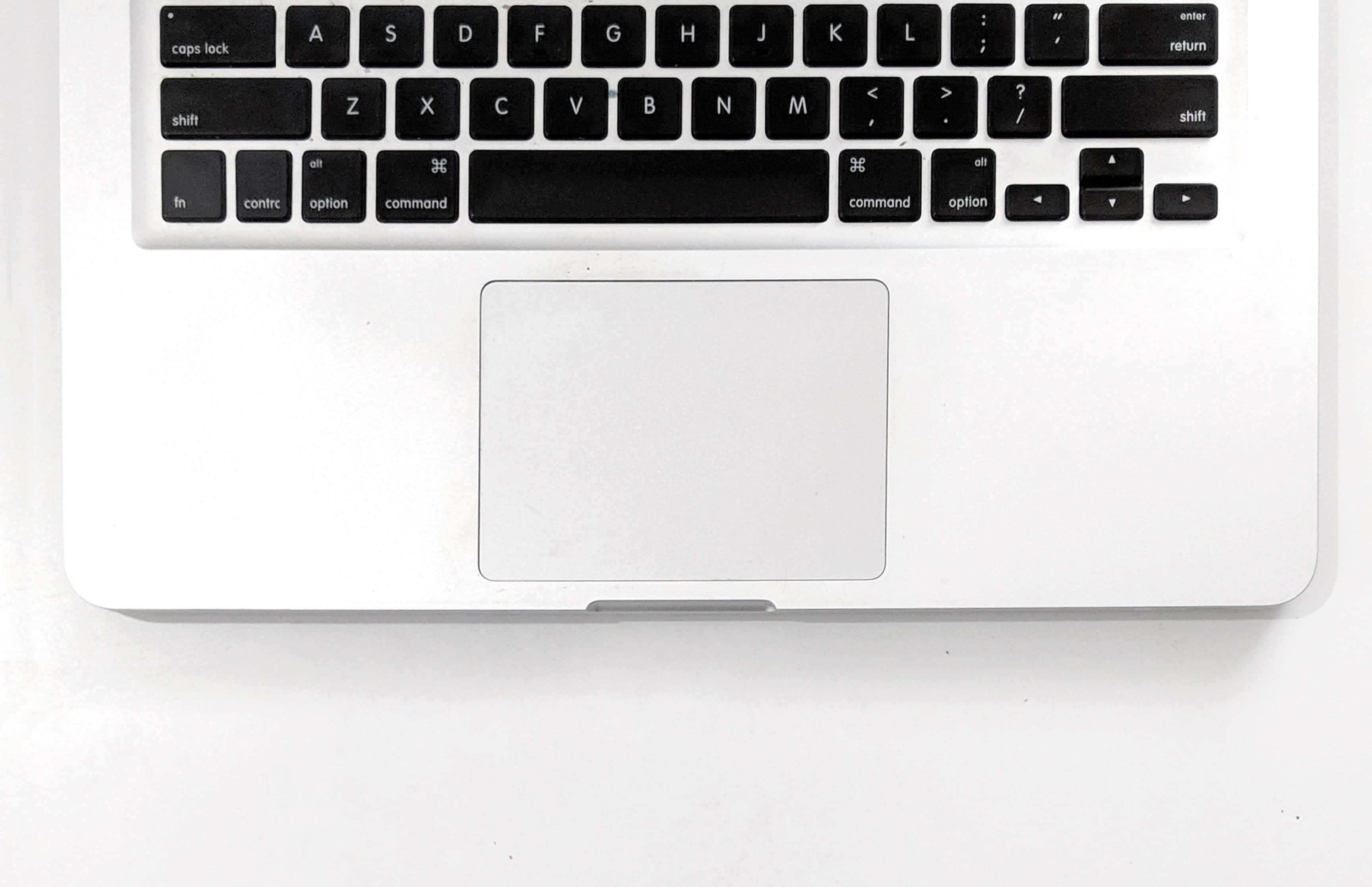 macbook pro 桌布 壁紙 — 從上方俯瞰一個時尚的銀色筆記型電腦鍵盤和觸控板，置於潔白表面上。