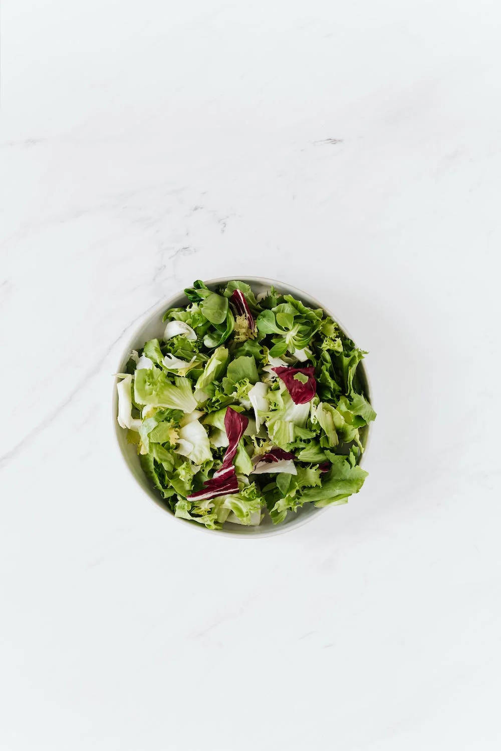 Vegetables 桌布 壁紙 — 從上方俯瞰一個白色碗中的新鮮混合綠色沙拉，放在乾淨的大理石表面上。