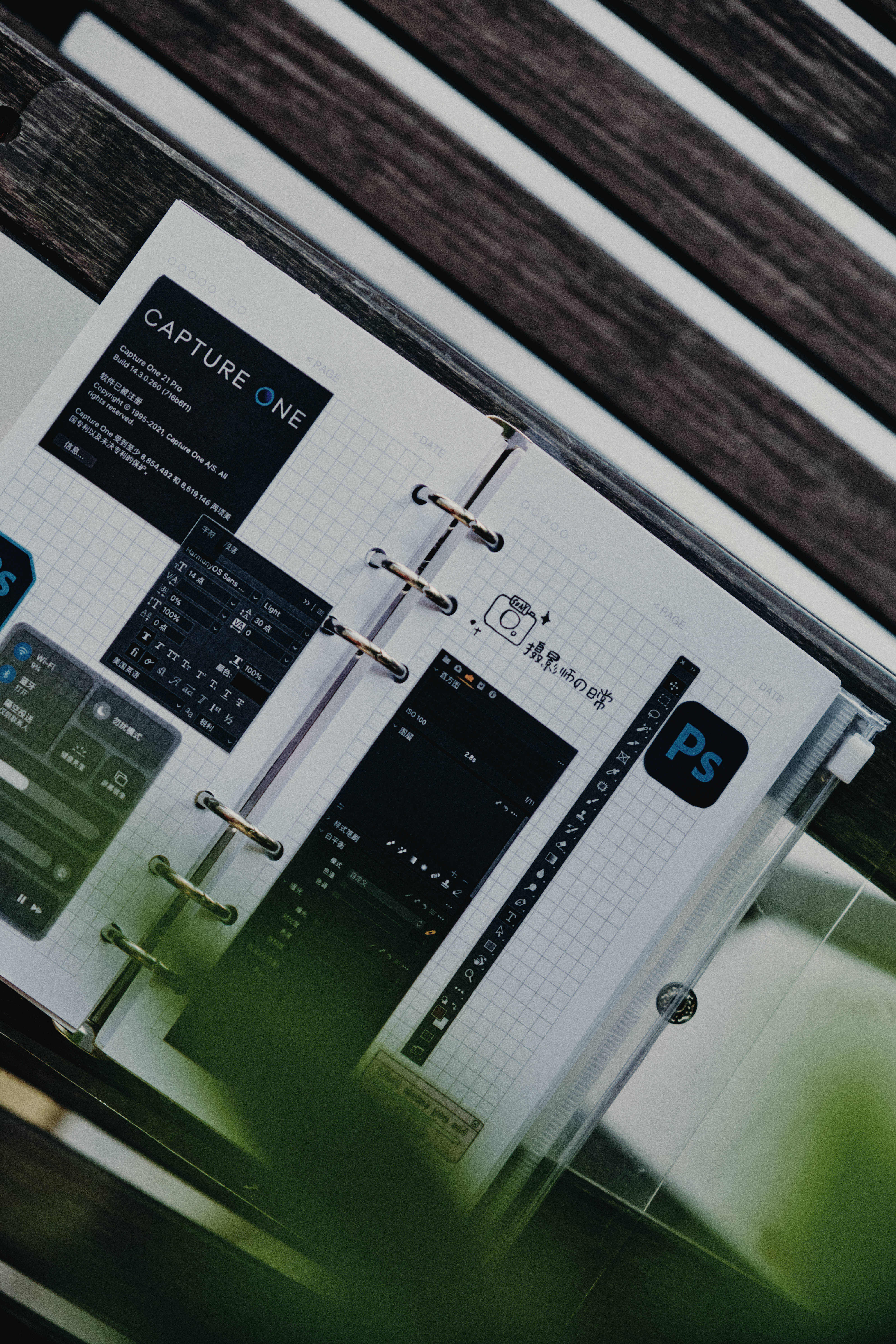 編輯 桌布 壁紙 — 從上方俯瞰一個計劃本，上面印有 Photoshop 和 Capture One 應用程式介面，放在方格紙上，置於木質表面。