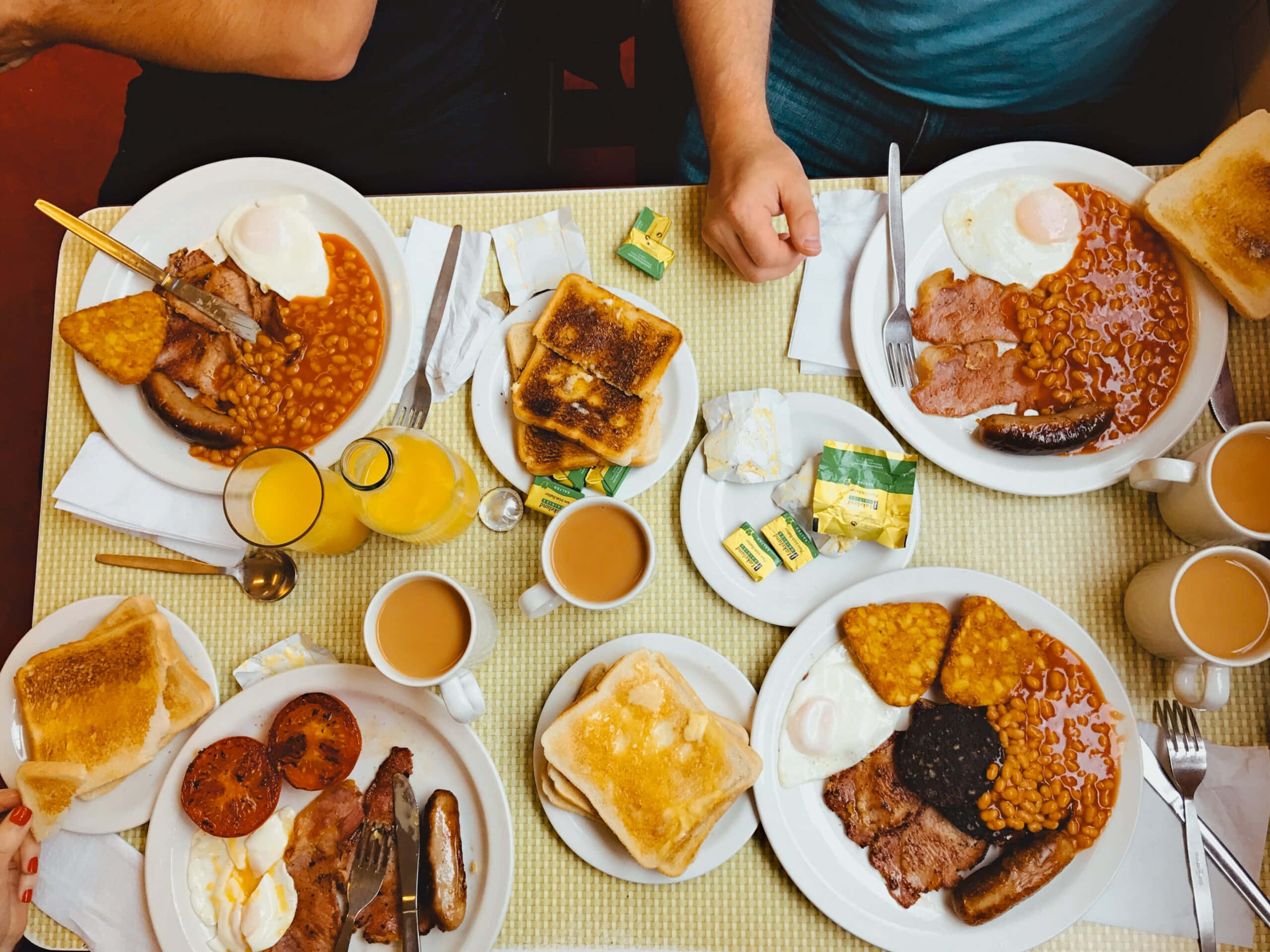 早餐 桌布 壁紙 — 從上方俯瞰一個豐盛的全英式早餐，有雞蛋、豆子、吐司和飲料，放在黃色格子桌布上。
