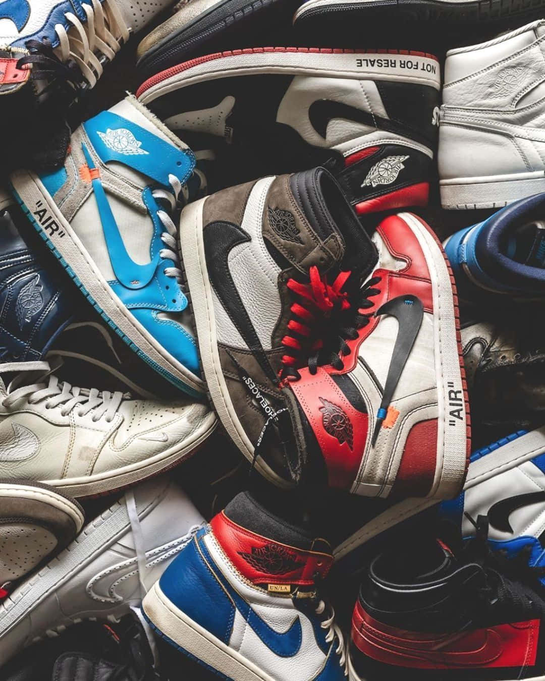Off White Jordan 1 桌布 壁紙 — 從上方俯瞰一堆色彩繽紛的運動鞋聯名款式，帶有搶眼的紅、藍、白配色。