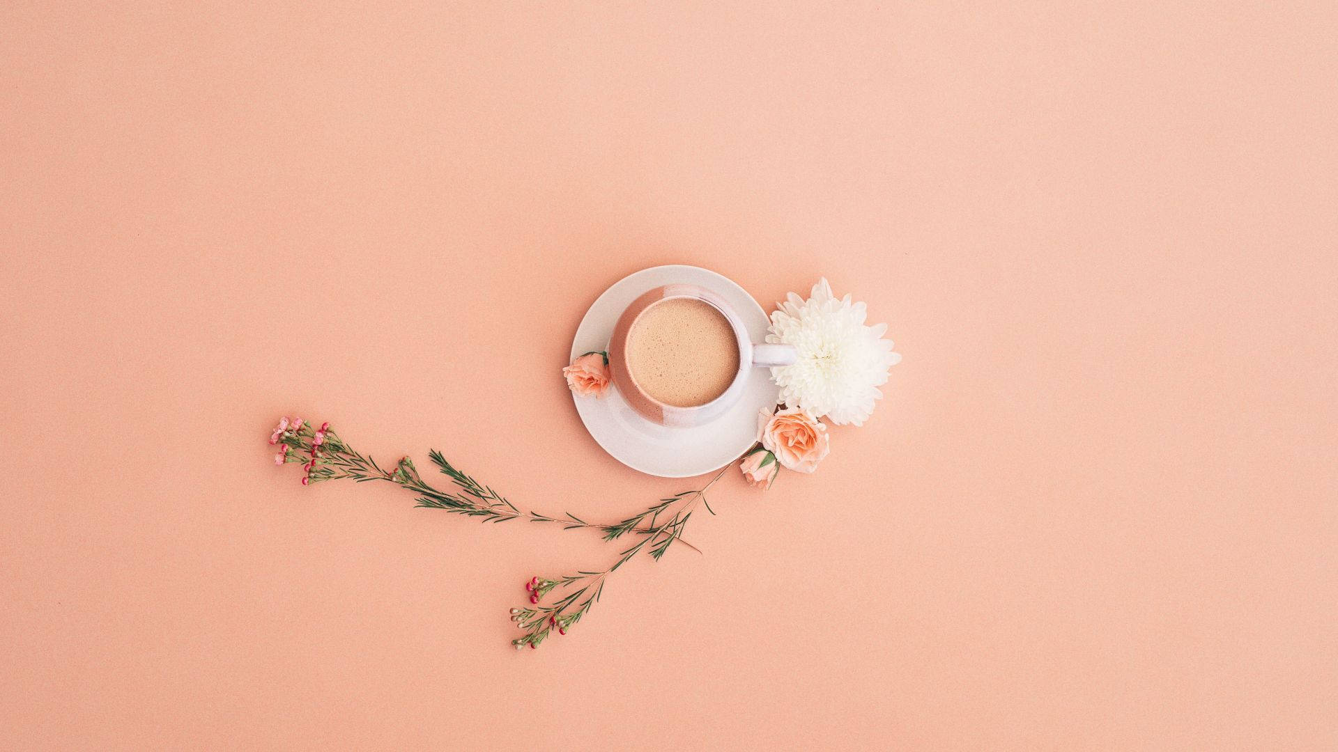 Minimalist Flower Computer 桌布 壁紙 — 從上方俯瞰一杯咖啡和精緻花朵，擺放在柔和的蜜桃色背景上。