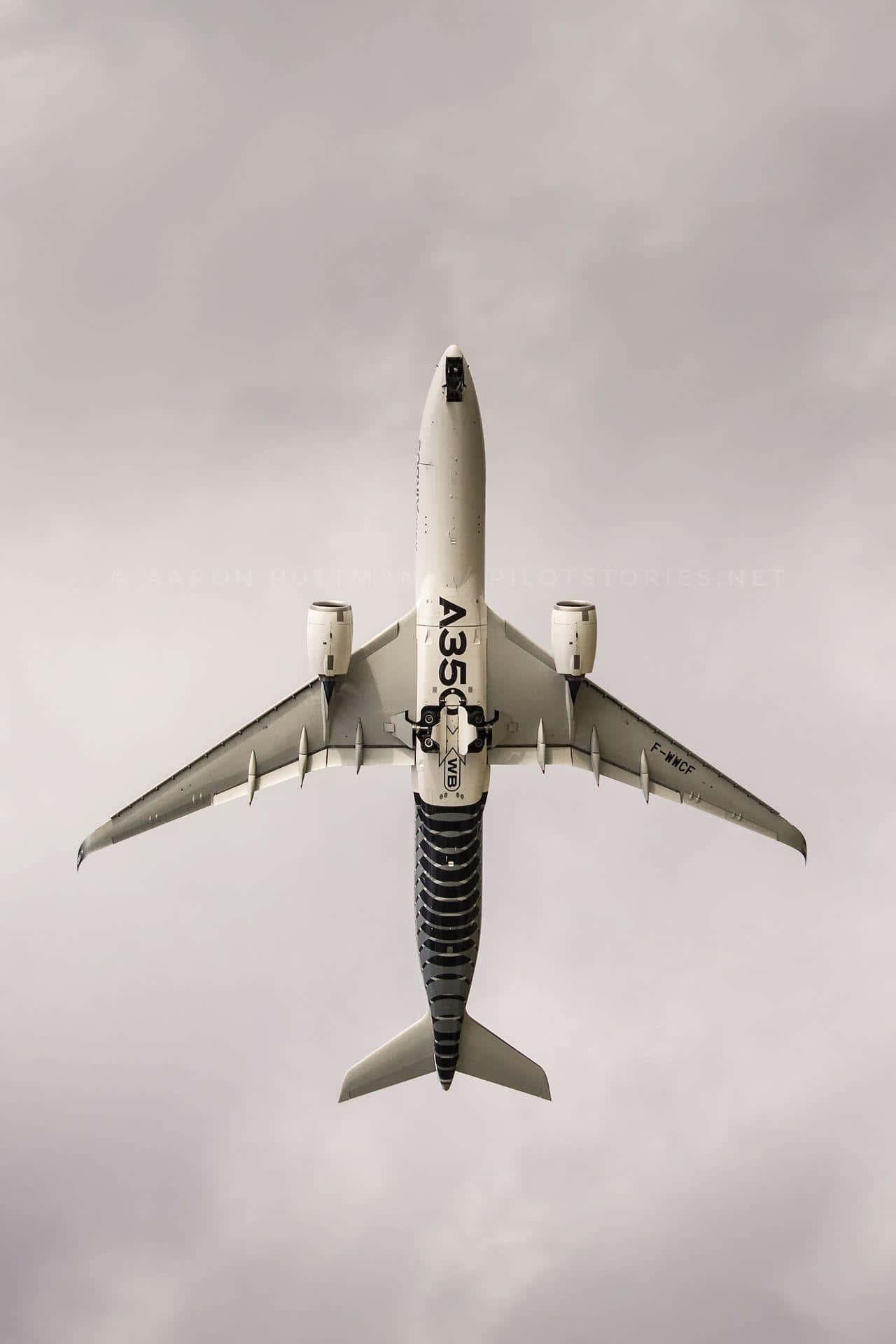 Plane 桌布 壁紙 — 從上方俯瞰一架白色空中巴士A350在陰天灰色天空中飛過。