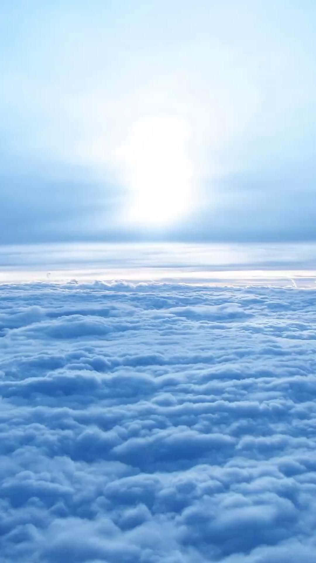 攝影 桌布 壁紙 — 從上方俯瞰一片廣闊柔軟藍色雲海的寧靜景色，明亮的太陽透過柔和薄霧閃耀。