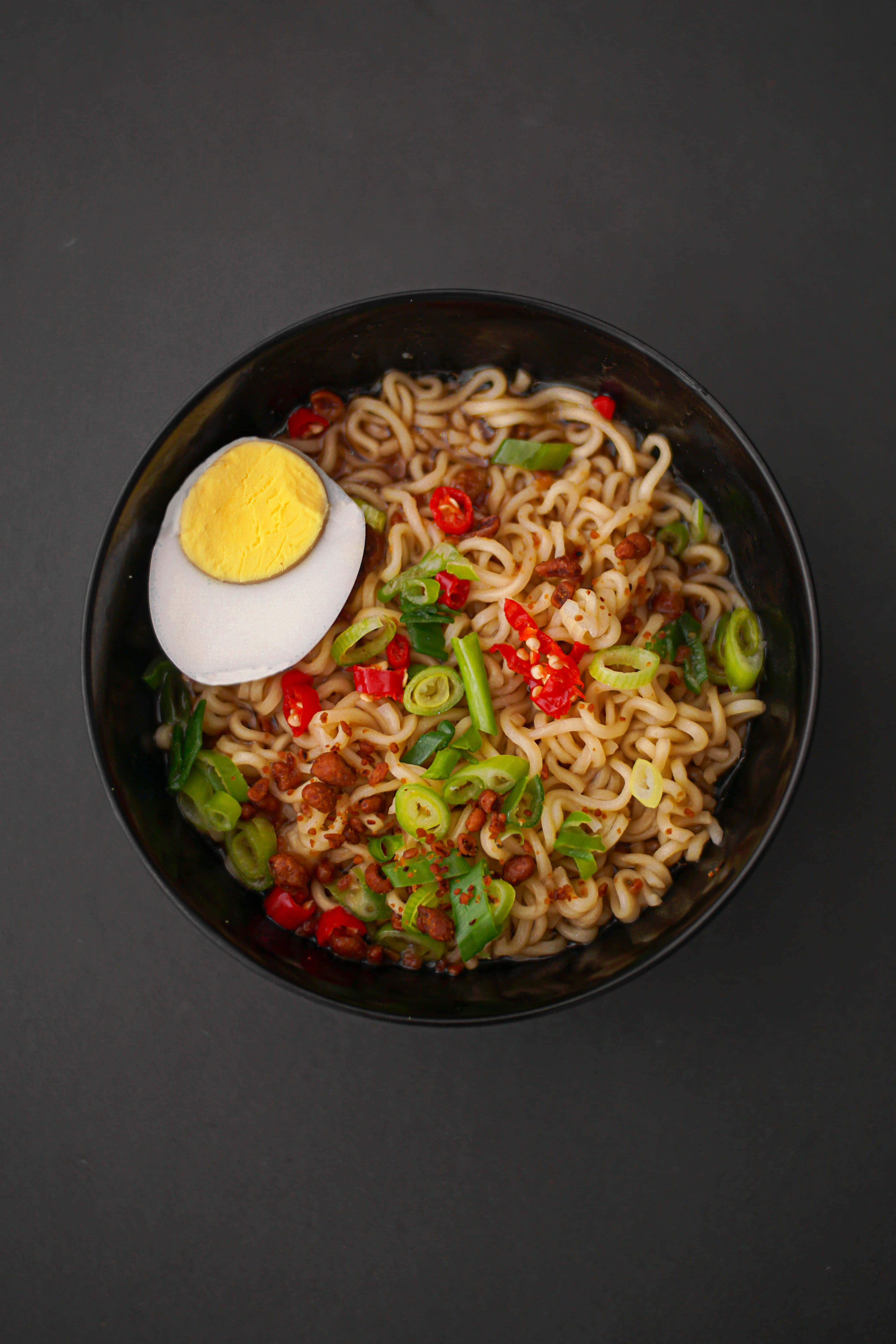 Noodles 桌布 壁紙 — 從上方俯瞰一碗冒煙的辛辣拉麵，上面放著半個水煮蛋和切碎的辣椒。