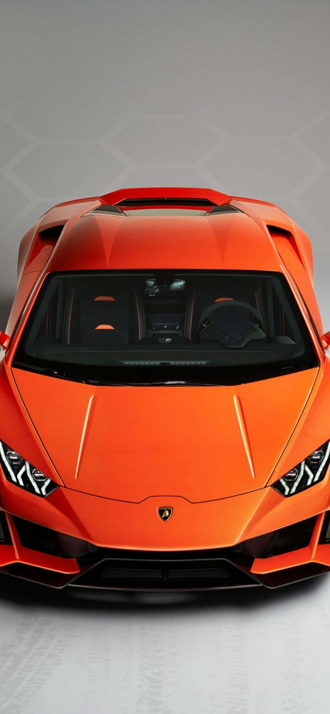 iPhone X Lamborghini 桌布 壁紙 — 從上方俯瞰一輛充滿活力的橙色藍寶堅尼跑車，背景為簡約的灰色六邊形。